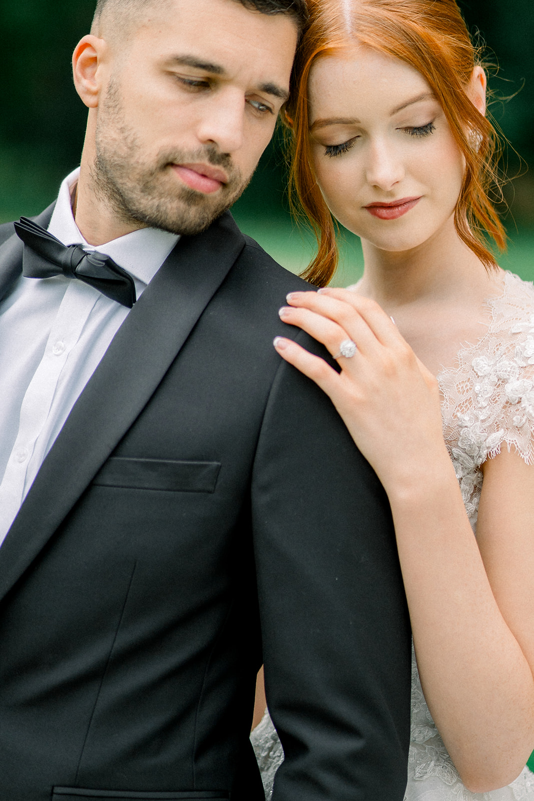 Close-up of a couple's intimate embrace, with focus on the bride's lace sleeve and the groom's black bow tie.