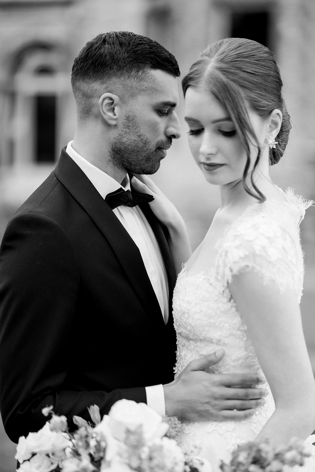 a couple's intimate embrace, with focus on the bride's lace sleeve and the groom's black bow tie.