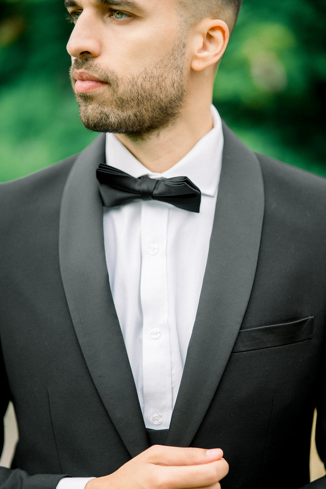 Groom in a classic black Paul Andrew suit, exuding sophistication against the lush greenery of Castle Leslie.