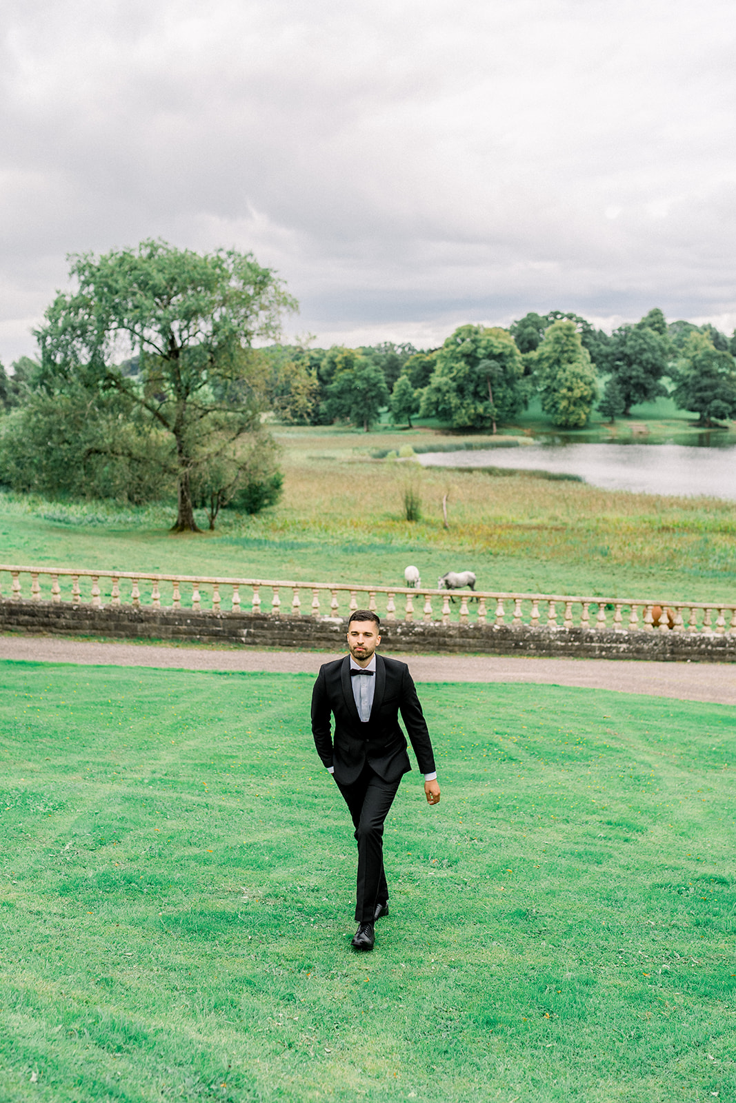 Groom in a classic black Paul Andrew suit, exuding sophistication against the lush greenery of Castle Leslie.
