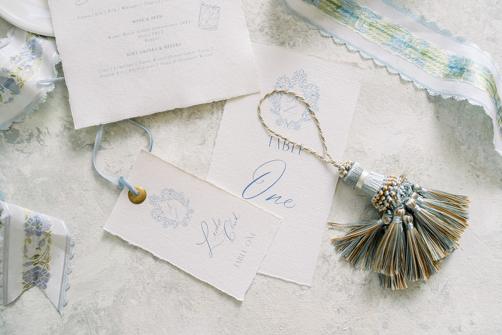 Stylish flat lay of wedding invitations and accessories, including Edera jewelry and a chic blue ring box from The Styli