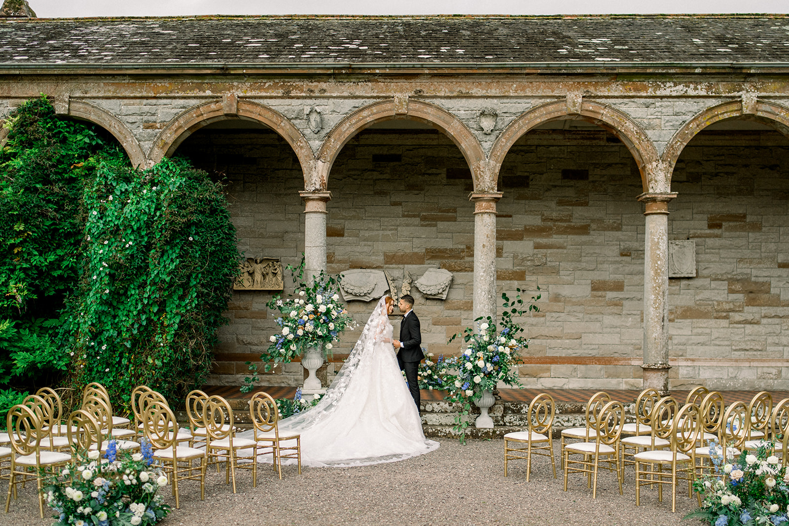 The bride and groom share a tender moment under a stone-arched ceremony at Castle Leslie, Ireland.