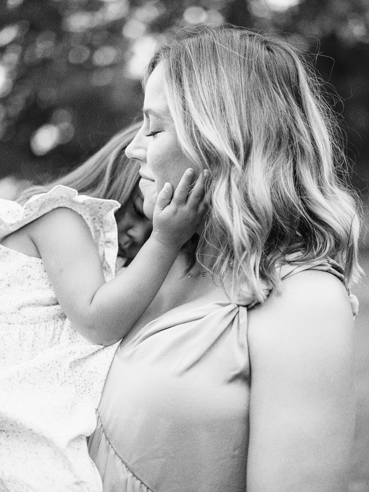 A daughter holds her mother's face in an intimate moment during a family maternity session by Kelsey Dawn Photography
