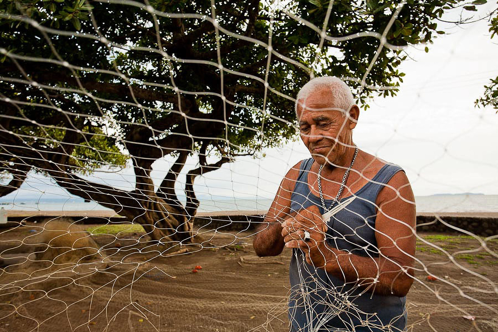 Fisherman fixing net with knife.
