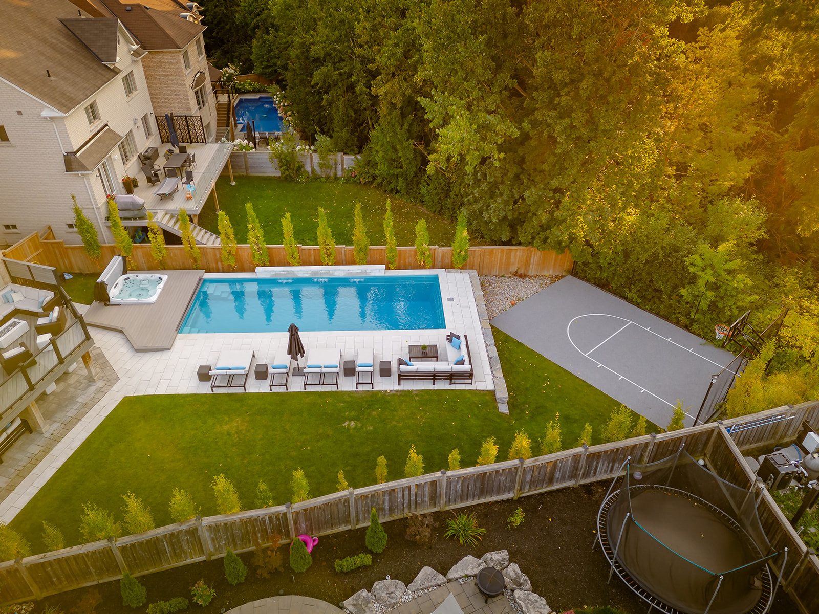 A drone-shot of the backyard and the inground pool and the basketball court.