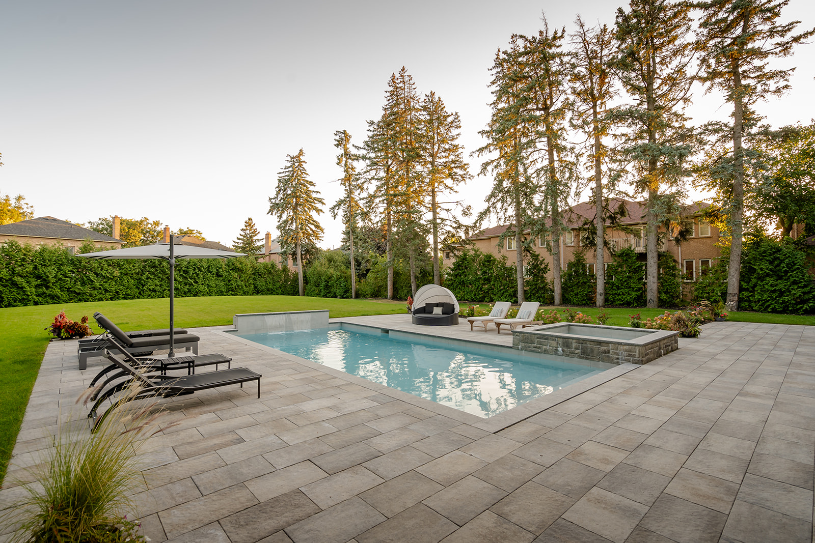 A backyard with an inground pool and the jacuzzi on the far right and outdoor furniture.