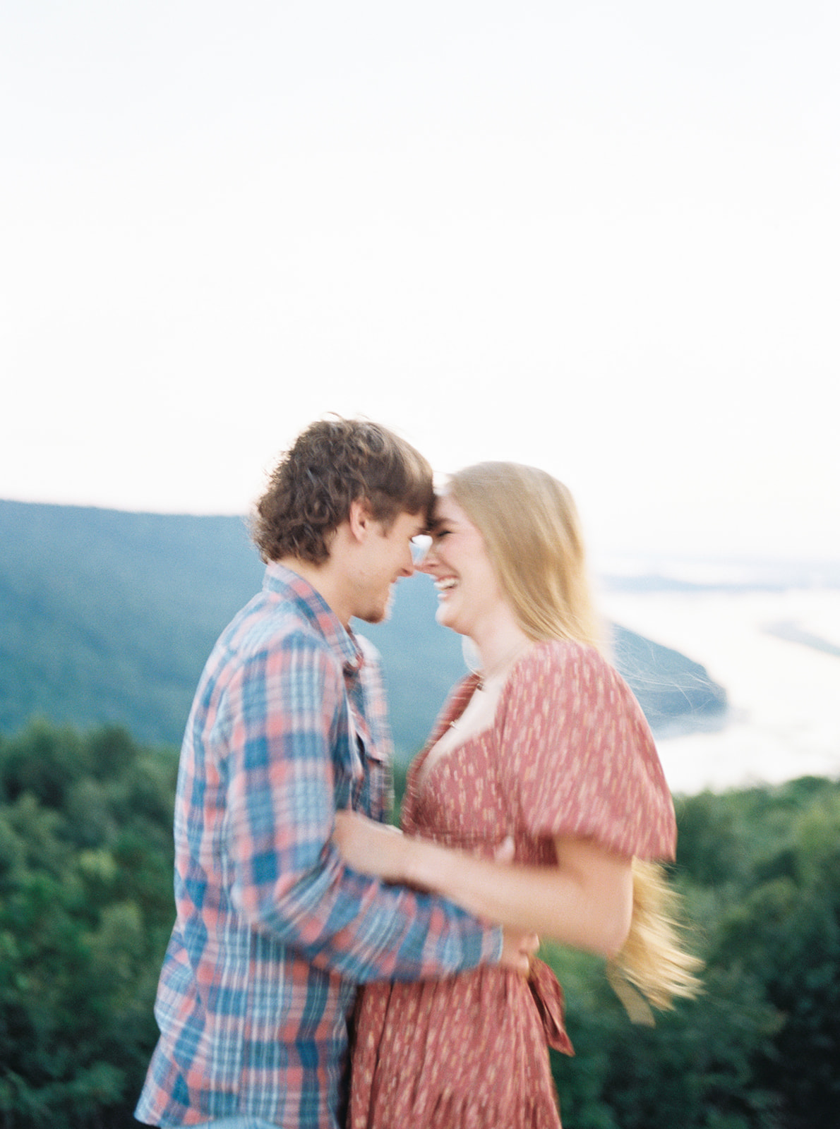An engaged couple share a laugh over an exquisite view of the lake below in Section, Alabama by Kelsey Dawn Photography