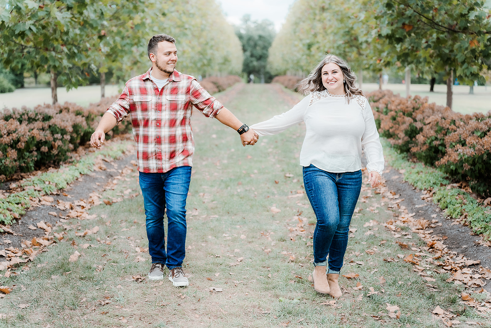 Casual engagement photo of couple walking down the corridor of trees Cox Arboretum Dayton Ohio