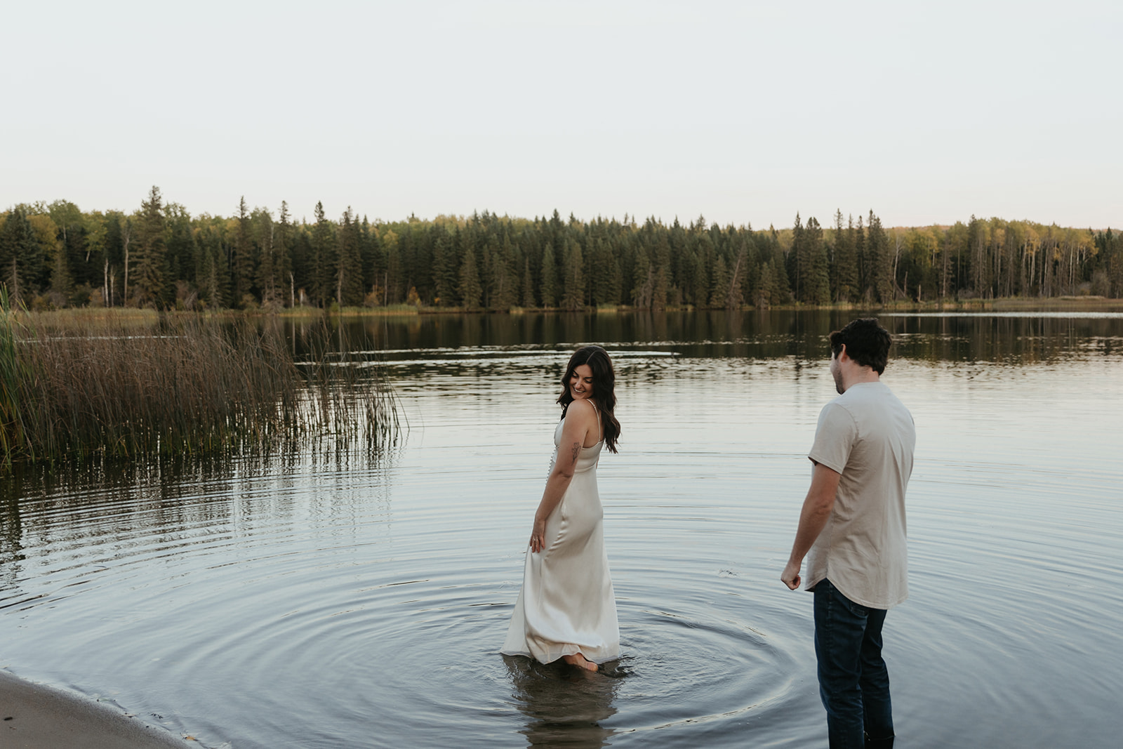 couple plays in the water at Long Lake at blue hour during their engagement session
