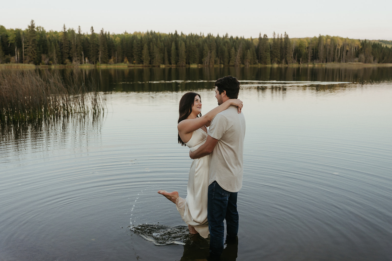 couple plays in the water at Long Lake at blue hour during their engagement session