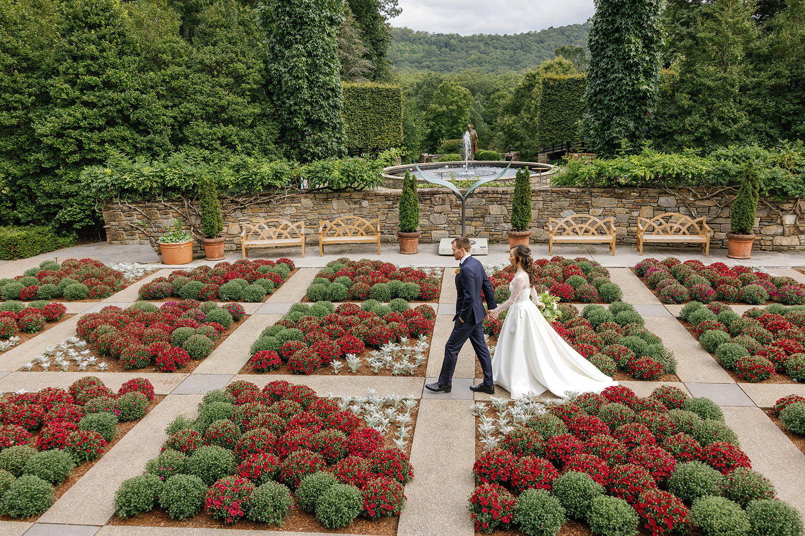 bride and groom walk through fall mums planted in the quilt garden at the NC arboretum 