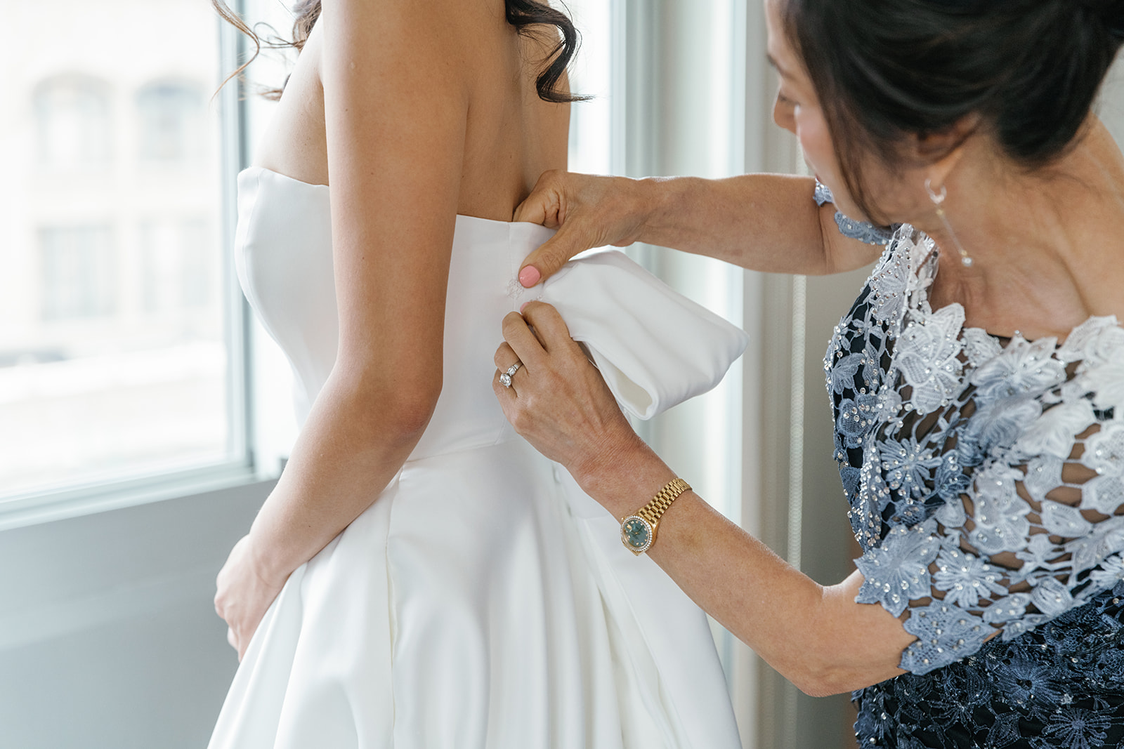 Mother of bride helps place bow detail to back of dress