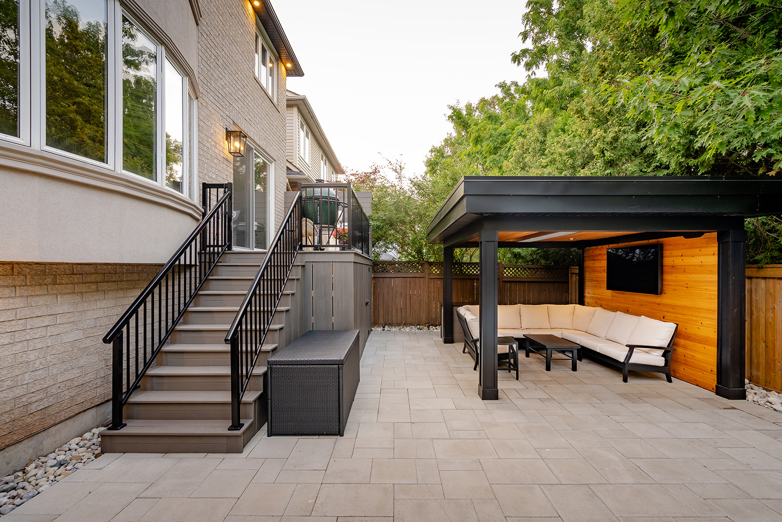 An outdoor seating area underneath a gazebo and stairs leading up to the house.