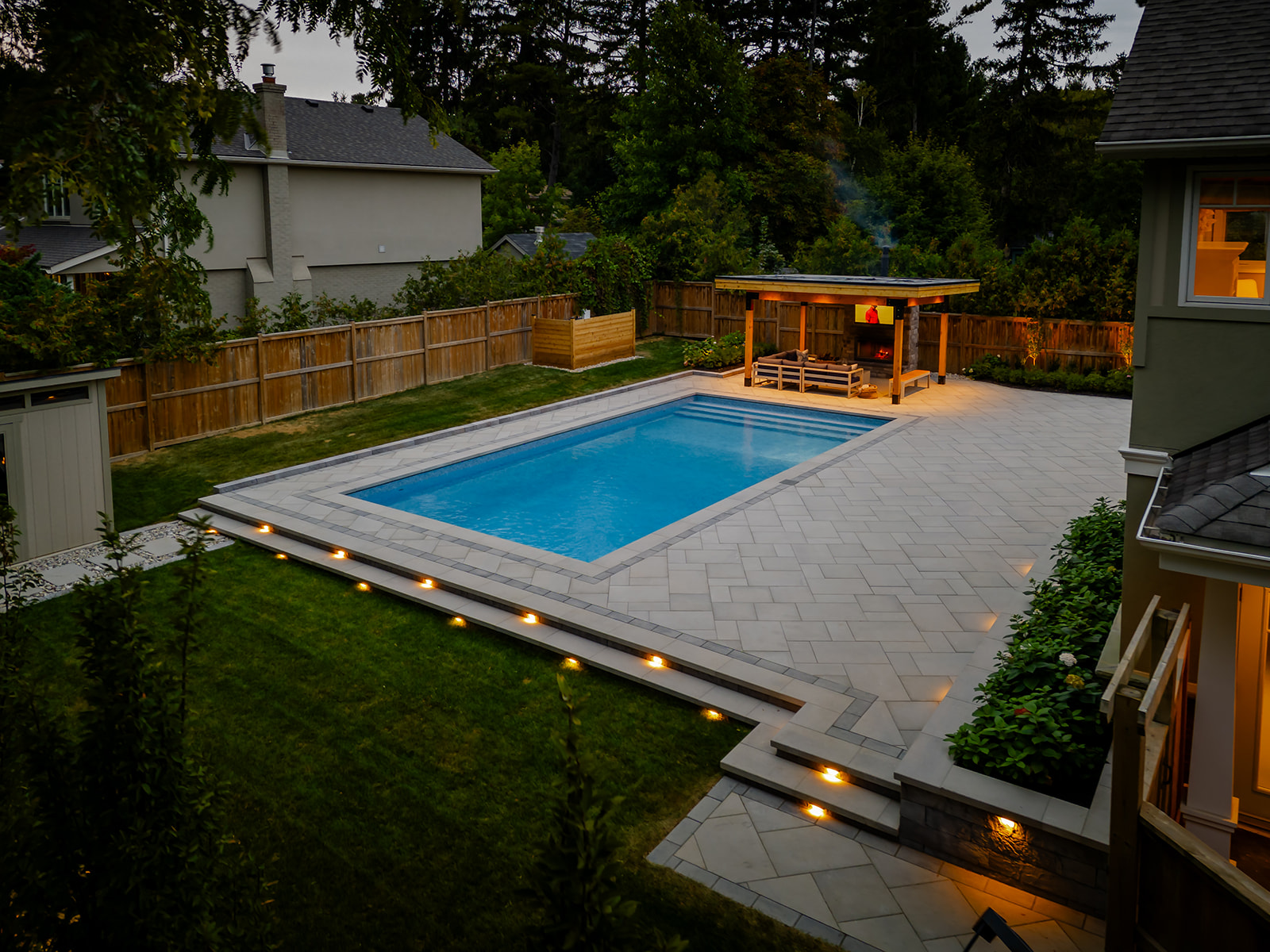 An inground pool in the backyard with a gazebo behind.