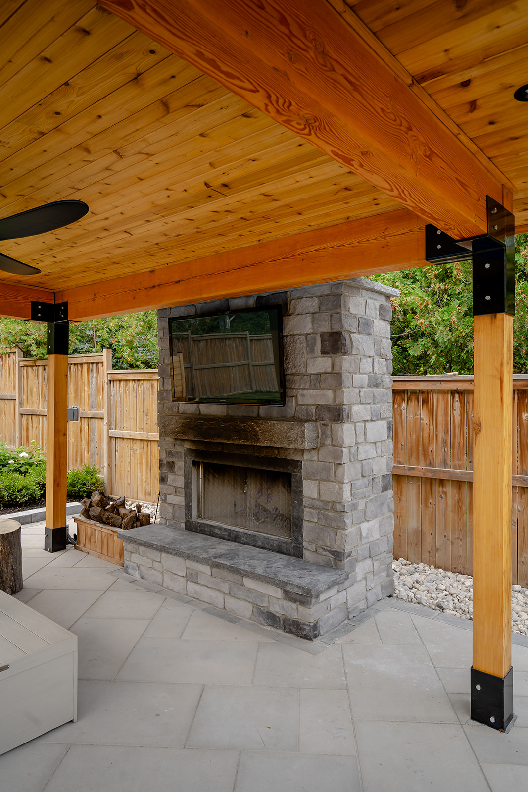 A large tv mounted to the brick wall underneath the gazebo.