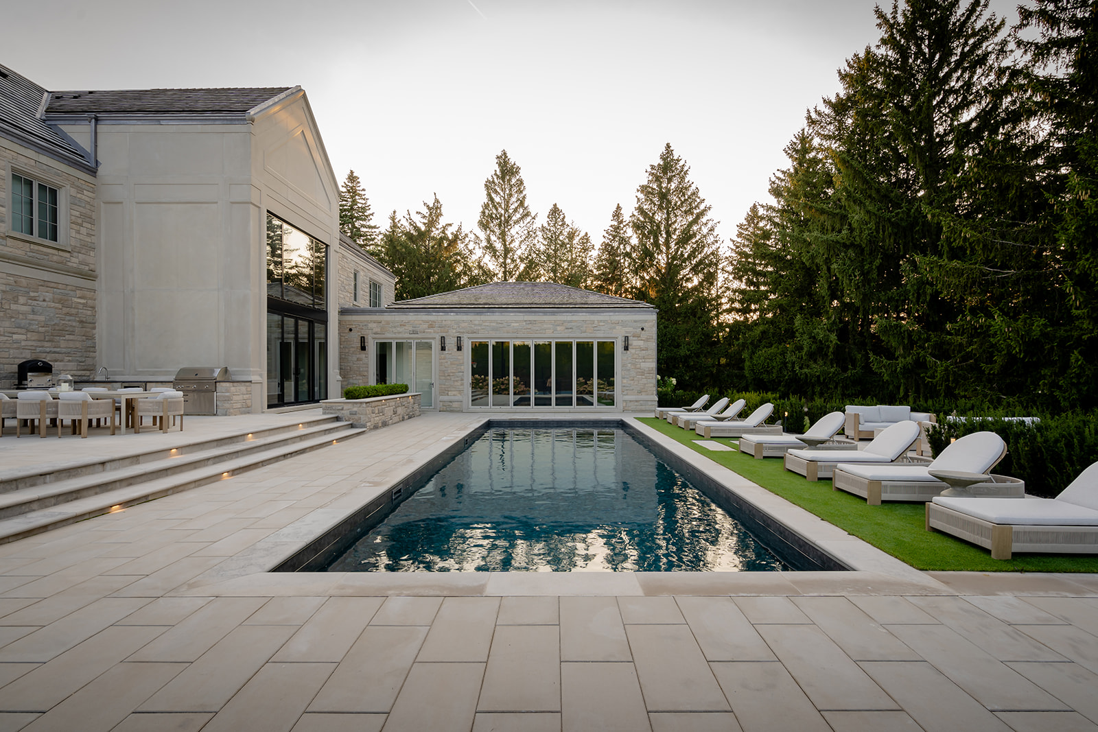 An inground pool with outdoor furniture on the right and the house on the left.
