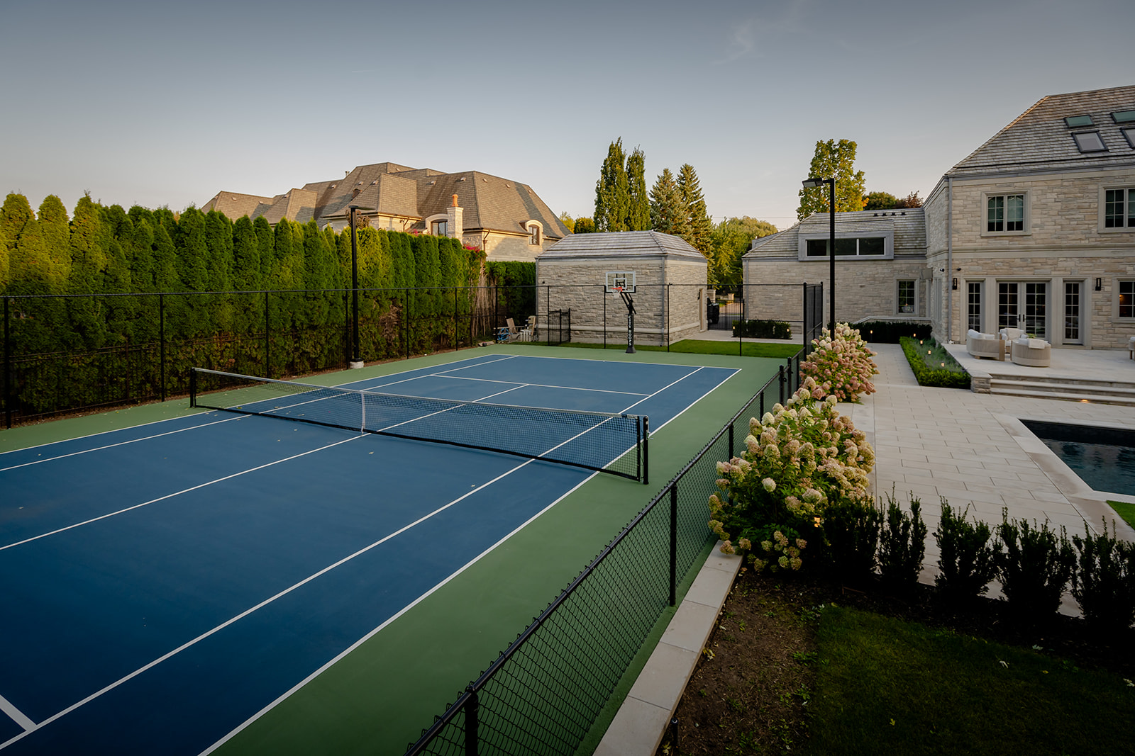 A large tennis court on the left with the house on the right.