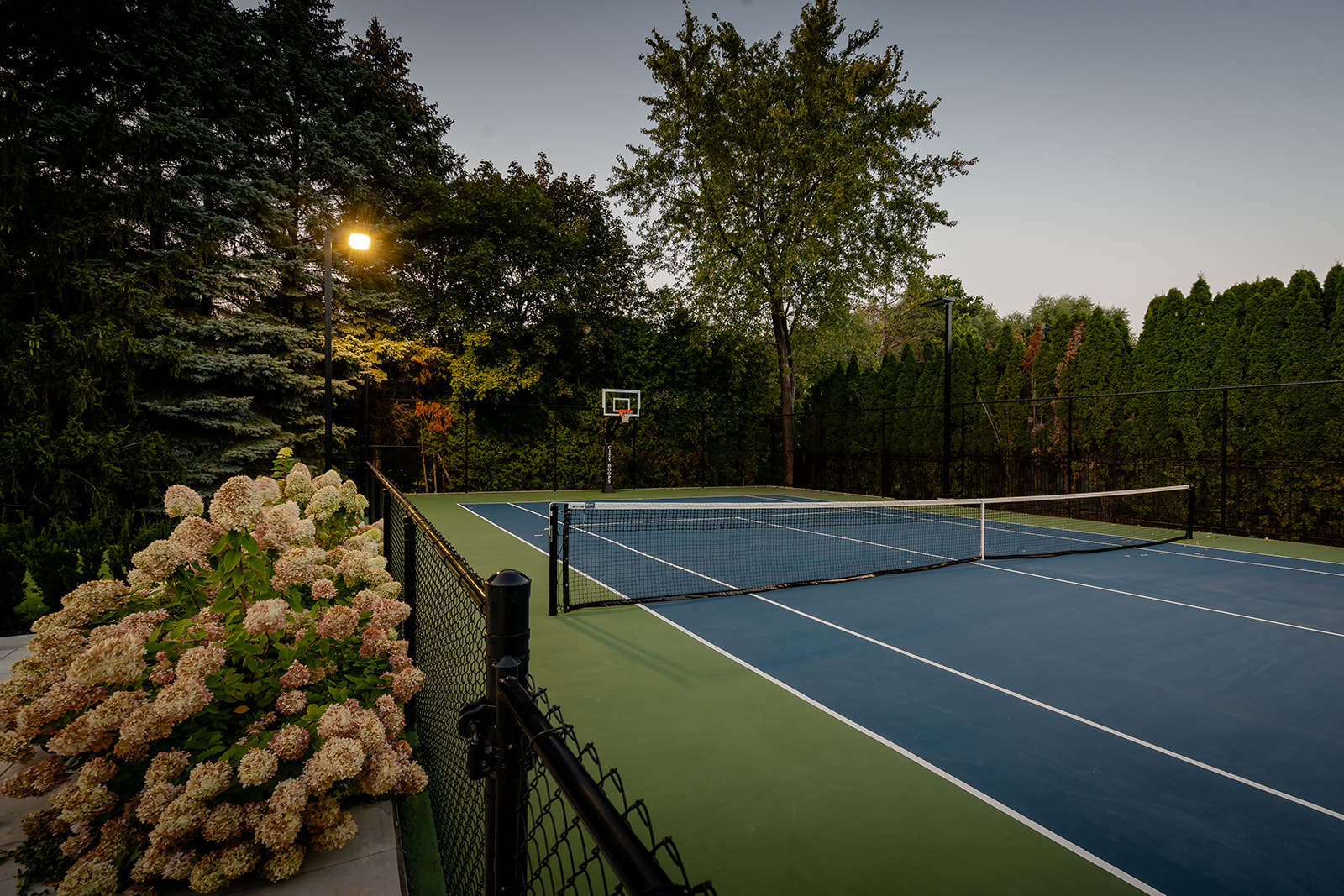 A large tennis court in the backyard.