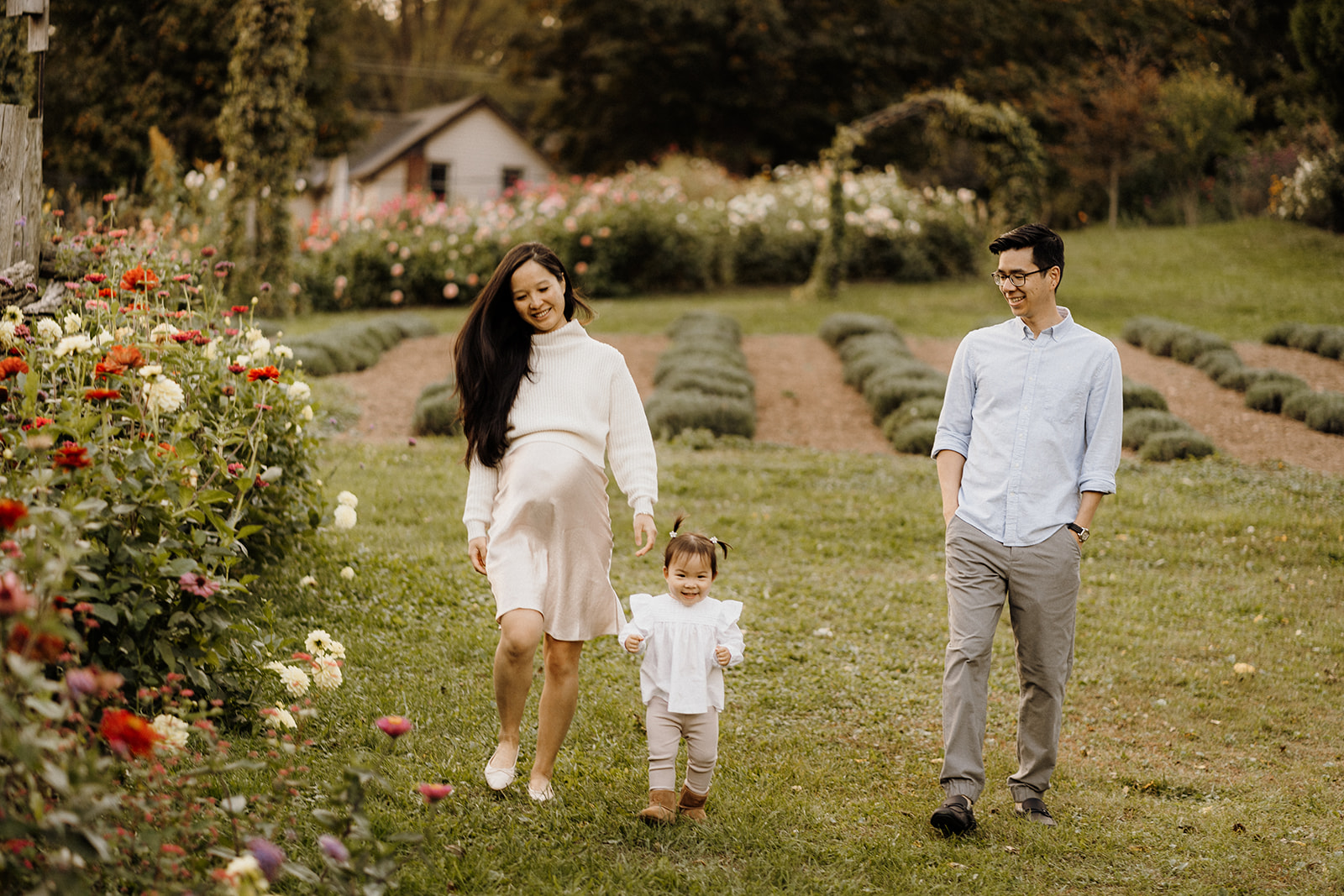 A family of three walking by the flowers.