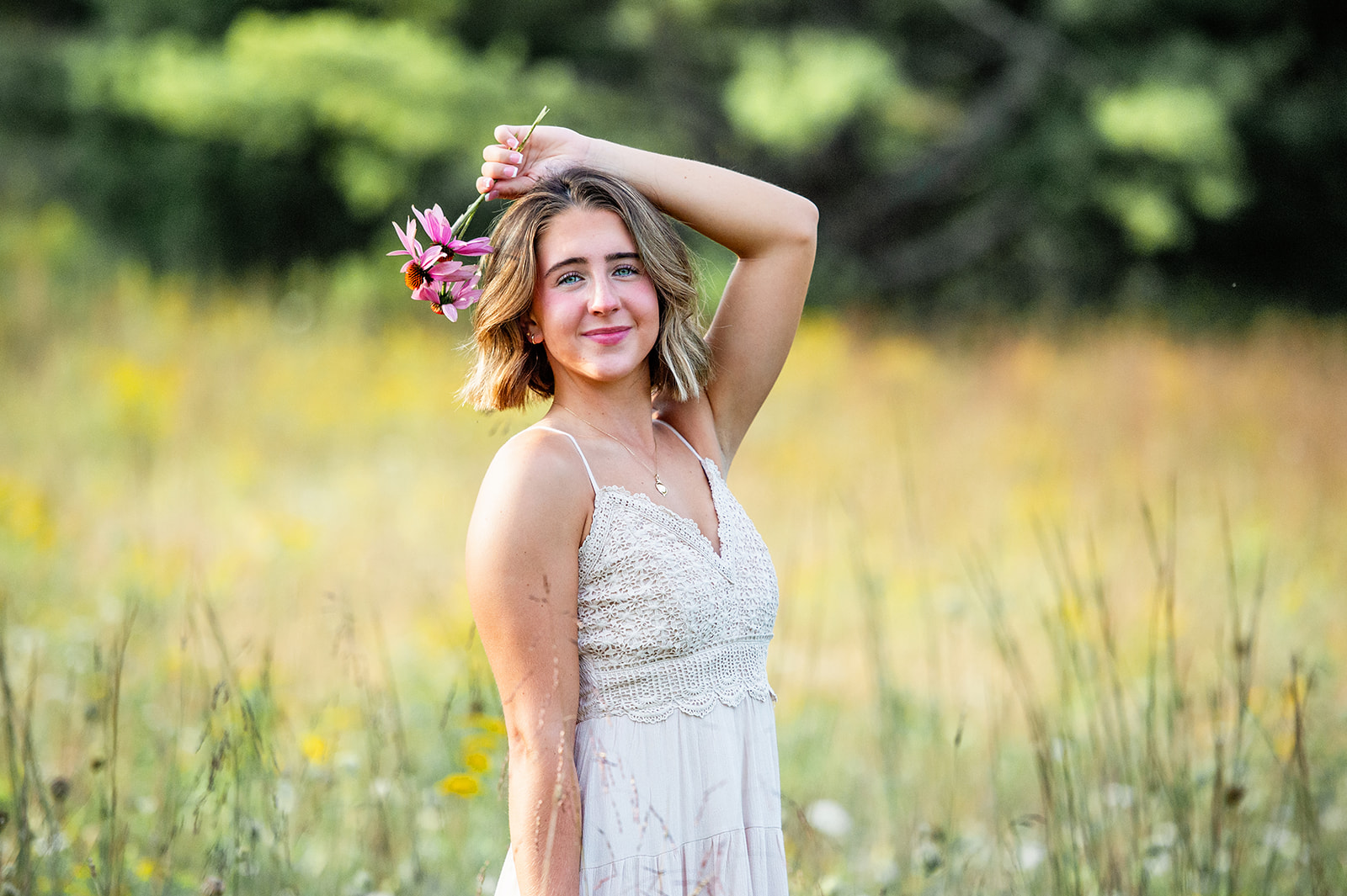 High school senior girl holding a wildflower over her head in a wildflower field. 