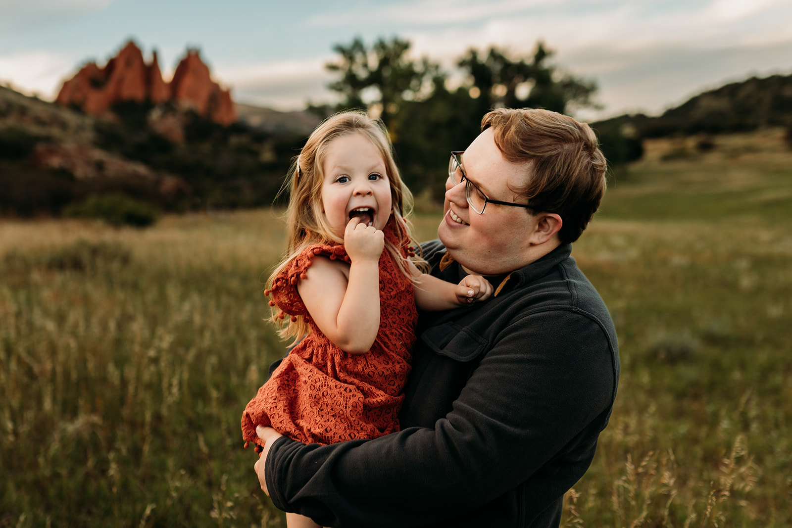 Dad snuggles his daughter during a cute daddy and daughter photo taken at Garden of the Gods by Heather Ann Photography 