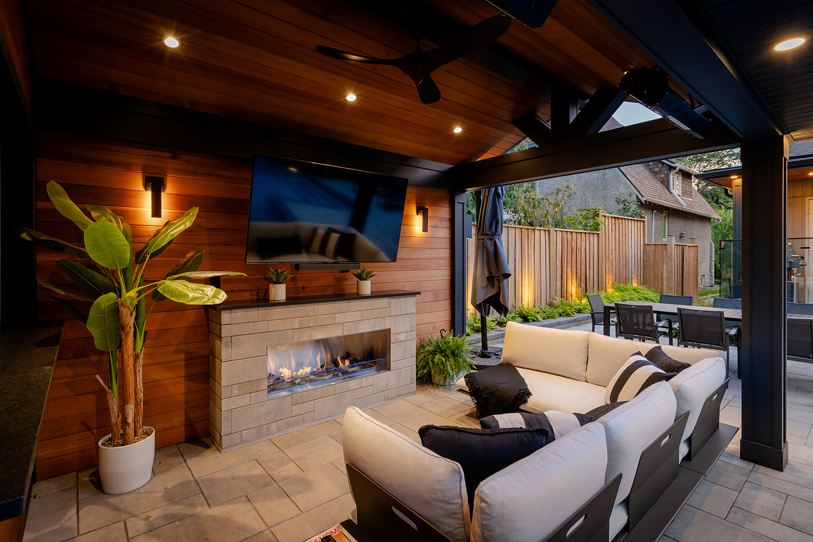 An outdoor furniture set with cushions and a tv mounted to the wall.