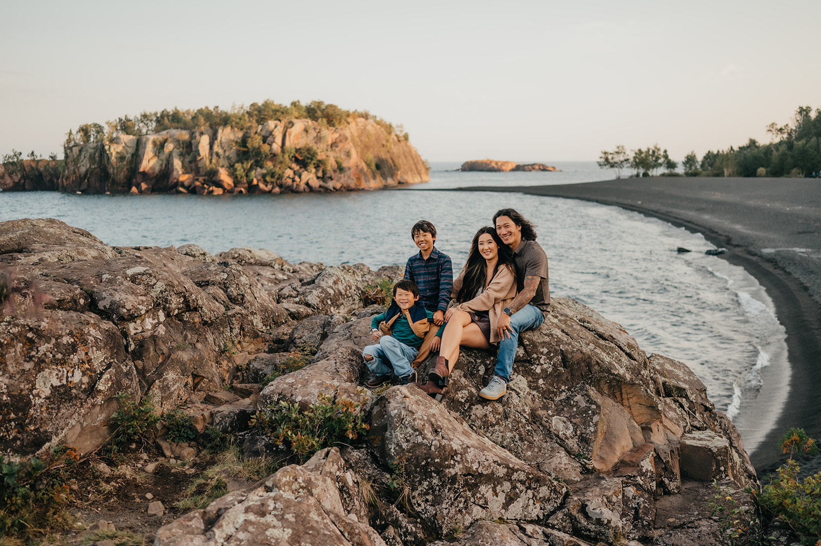 Family sitting on rocks overlooking Black Beach in Silver Bay, MN. 
