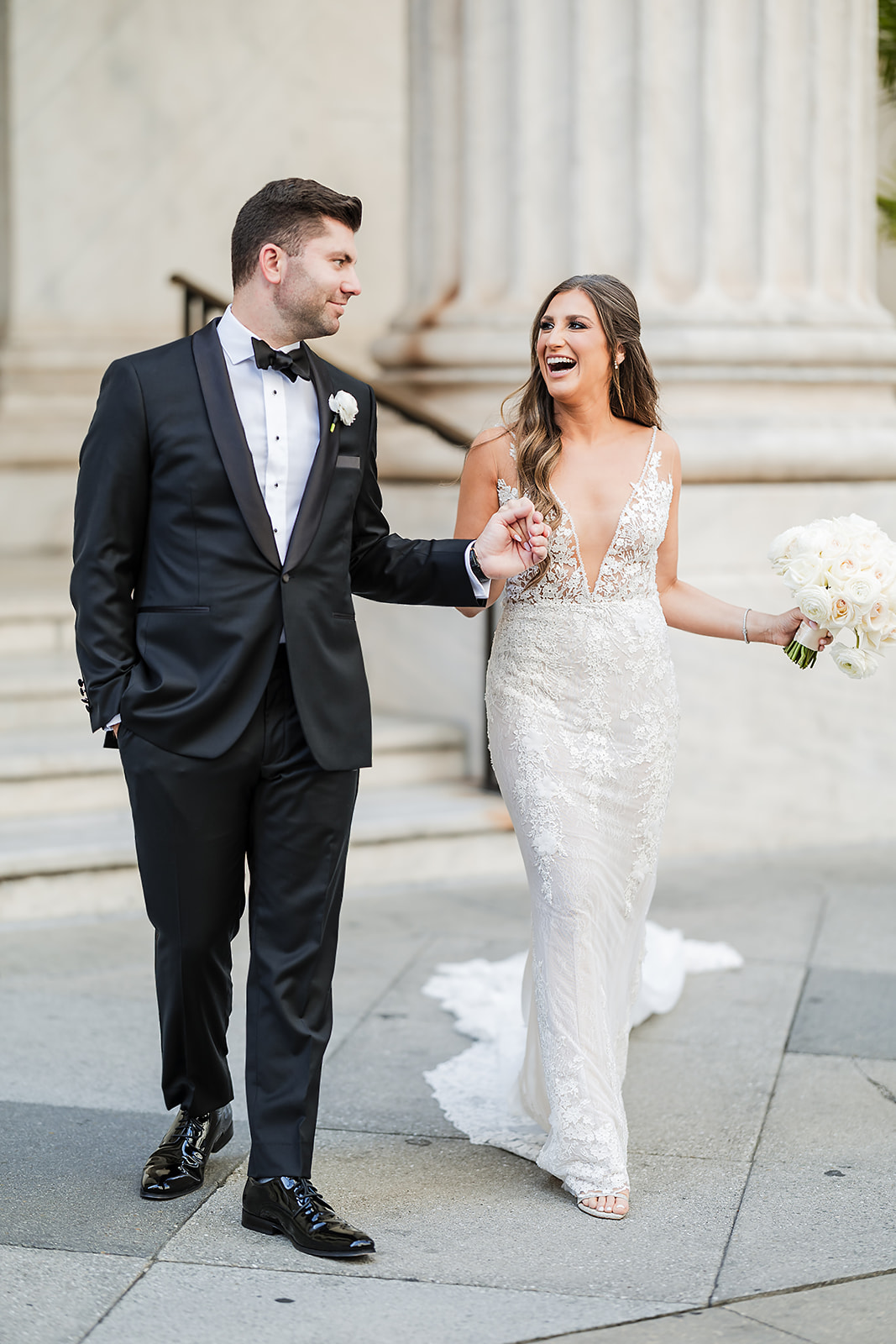 Bride and groom laughing effortlessly at the steps of the Ritz Carlton Hotel in Philadelphia
