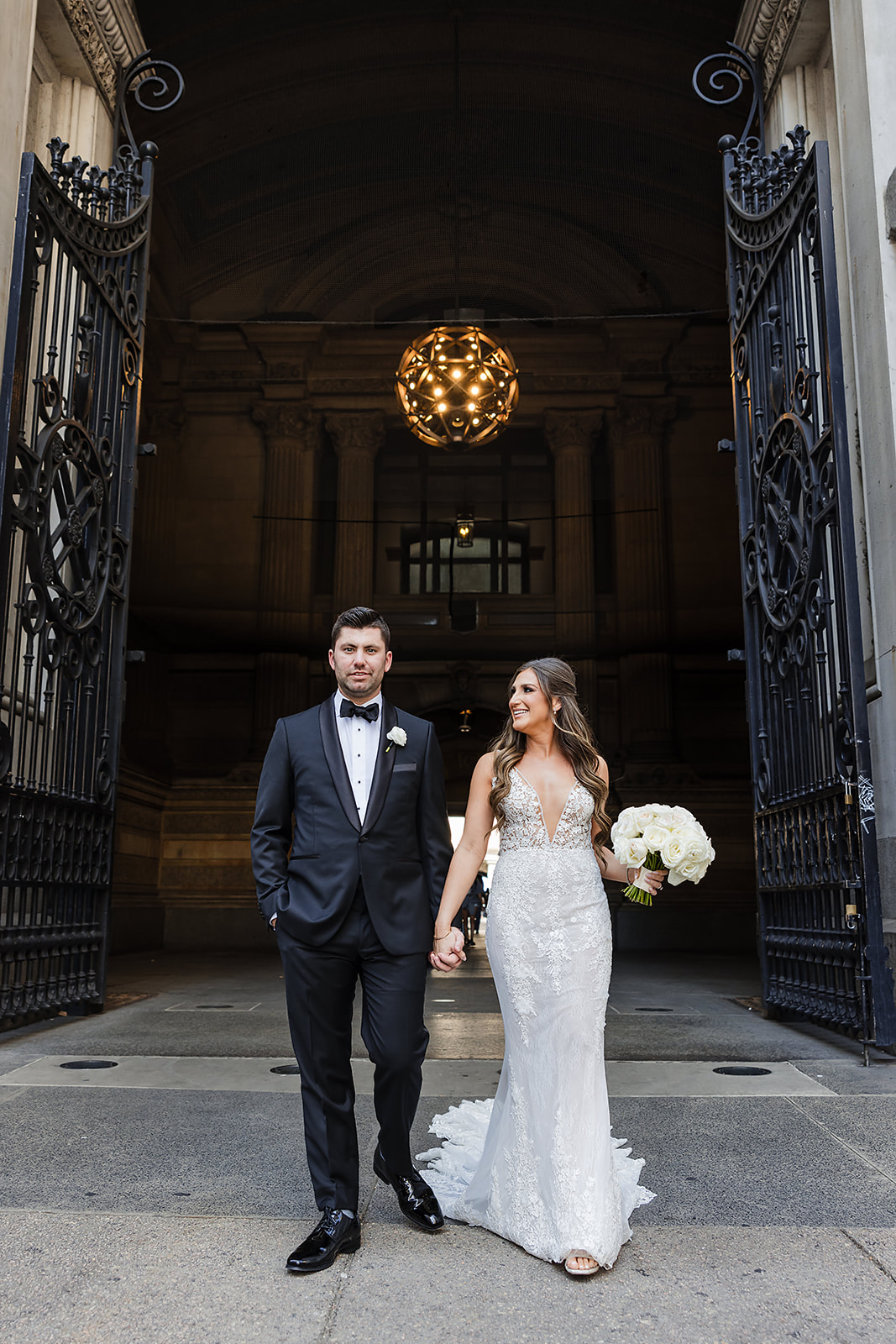 Wedding chic and effortless portrait of the bride and groom at City Hall Philadelphia walking and holding hands