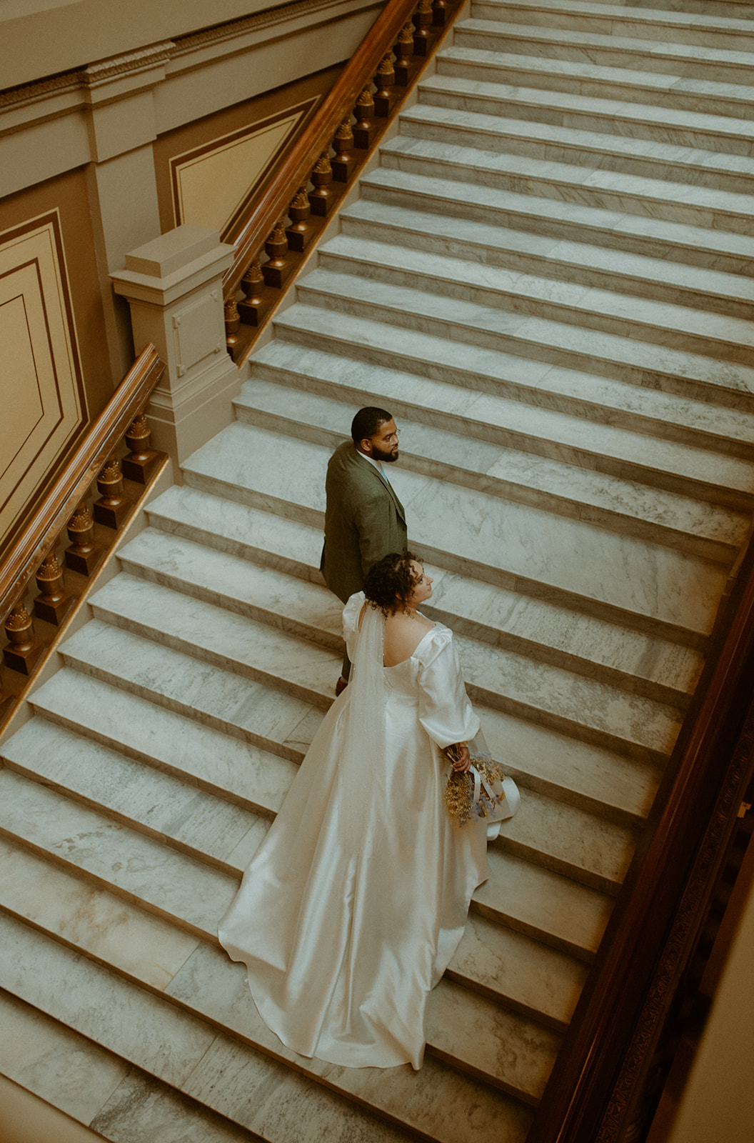 A couple getting married at the Indianapolis State House walking up stairs for portraits 