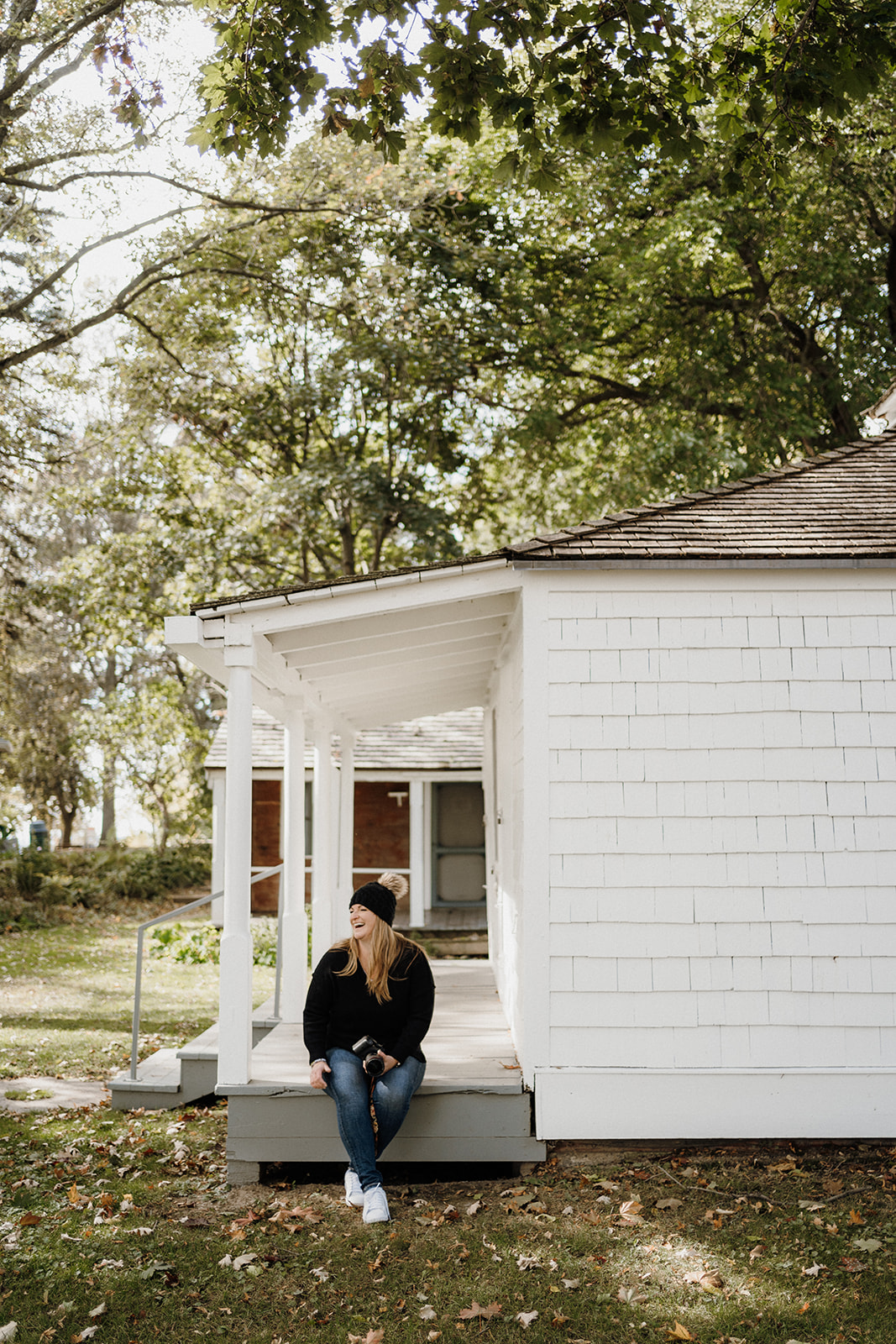 A lady sitting on the porch of a house.