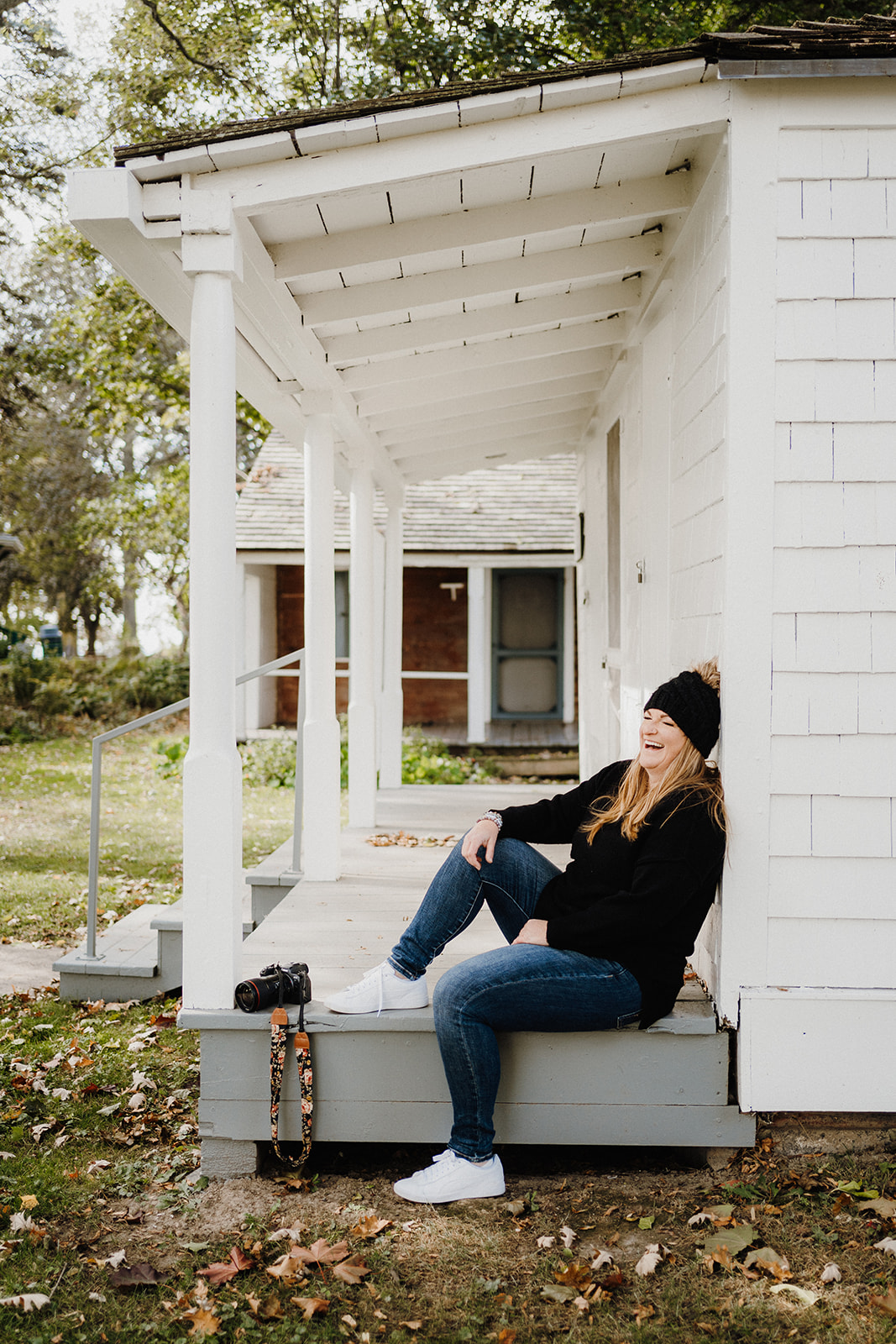 A lady sitting on the porch of a house.