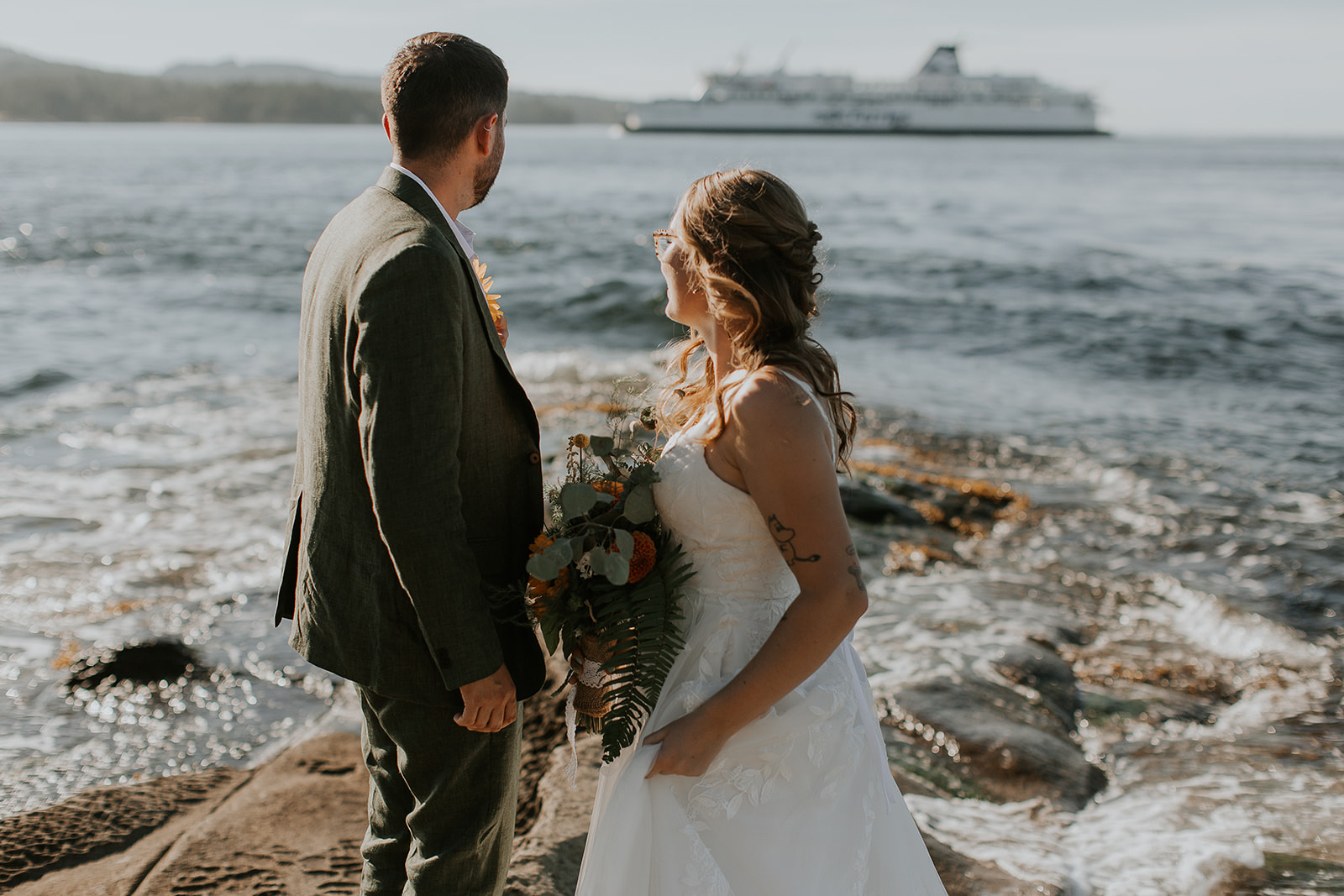 bride and groom watching ferry from Georgina point on mayne island, bc