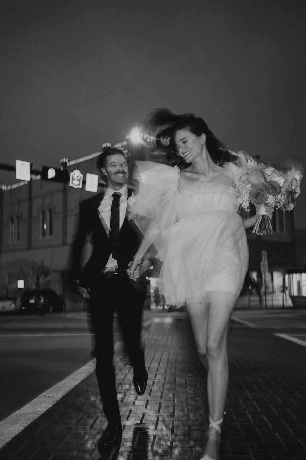 Bride and groom running downtown documented in a  black and white blurry photo