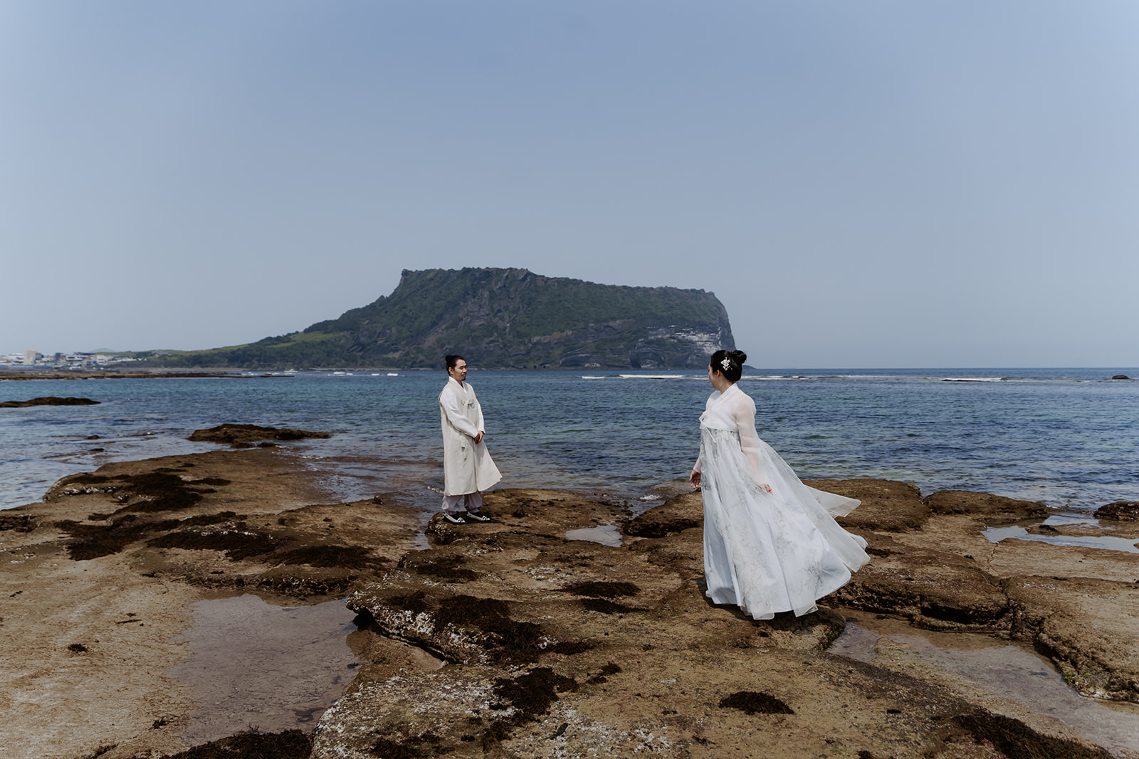 Asian couple standing on rocks near the ocean in Korea.
