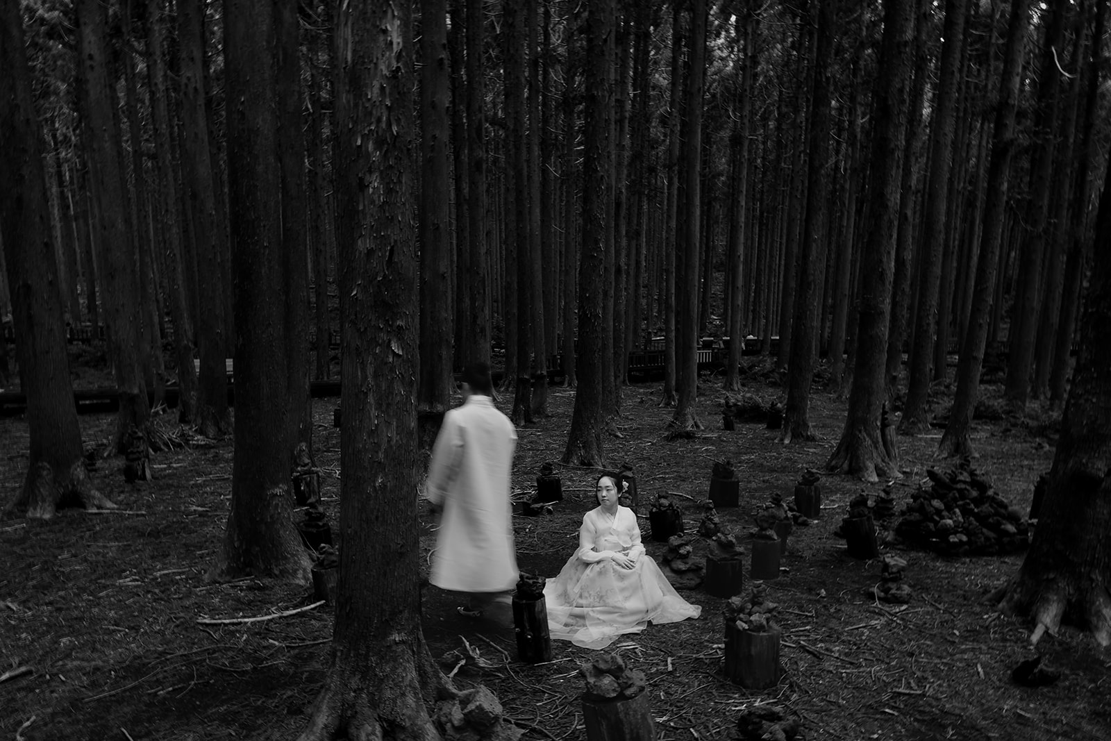 Pre-wedding, black and white photo of a couple in a wooded area.