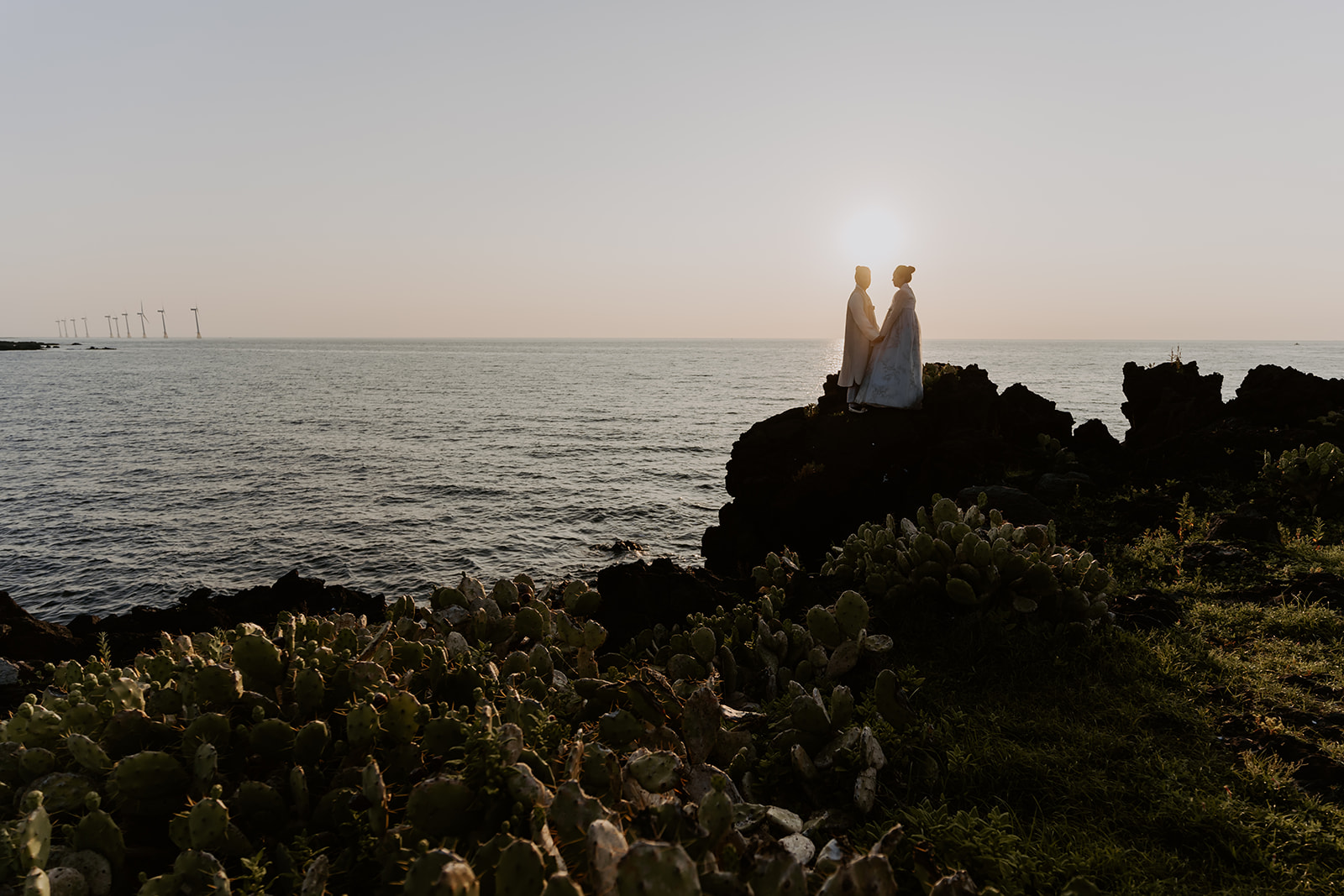 A pre-wedding couple standing on top of a cliff overlooking the ocean in Korea.