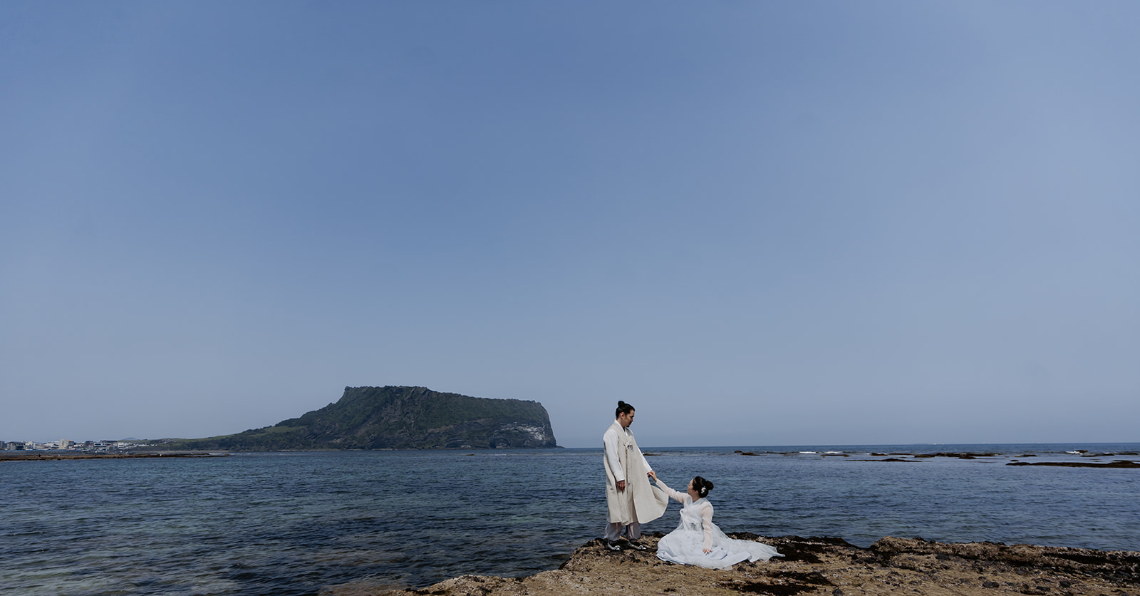 The couple stood on rocks near the ocean during their pre-wedding photoshoot in Korea.