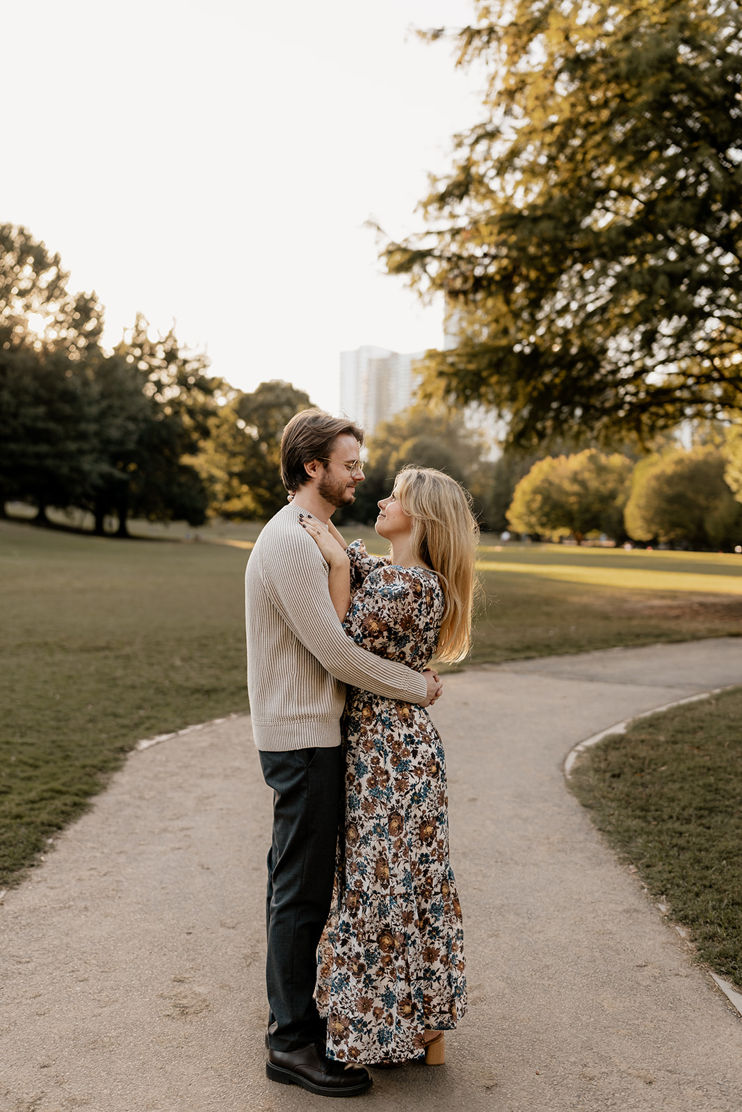 The couple's elegant attire complements the lush greenery of the park.
