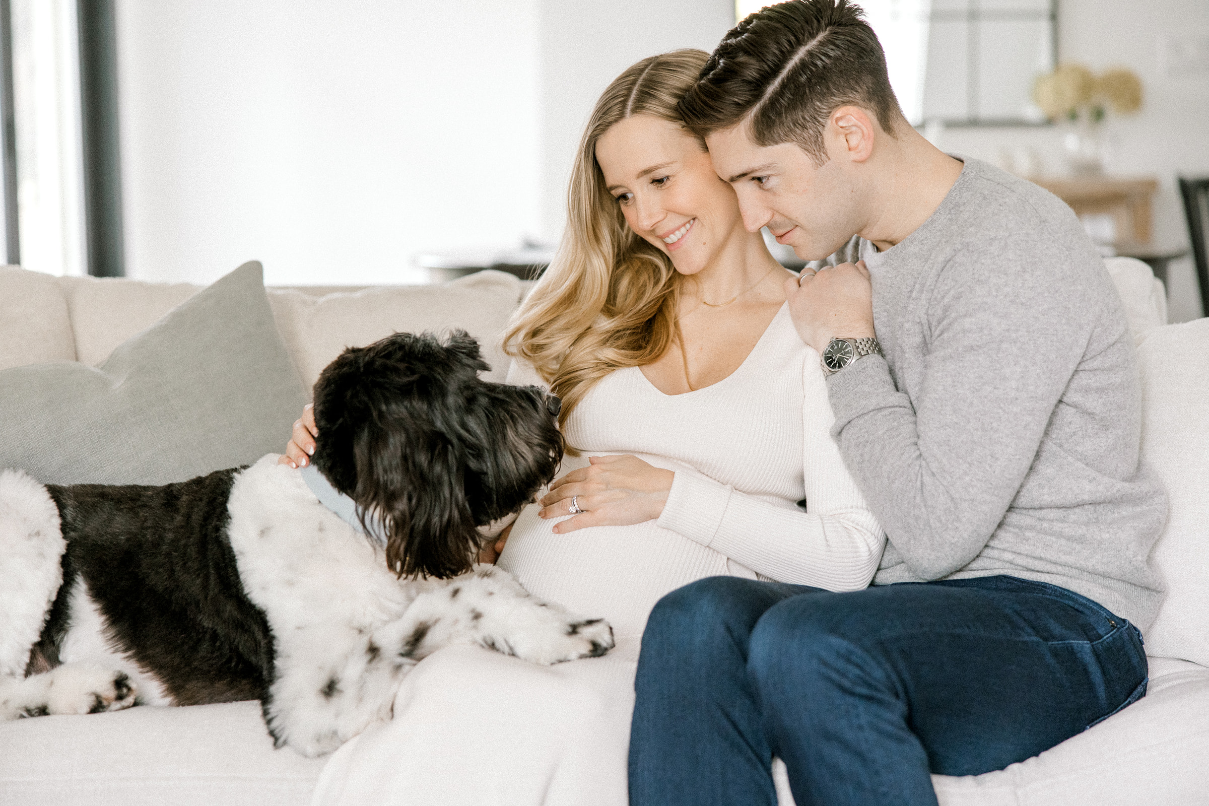 Couple snuggles on the couch during their at-home maternity shoot