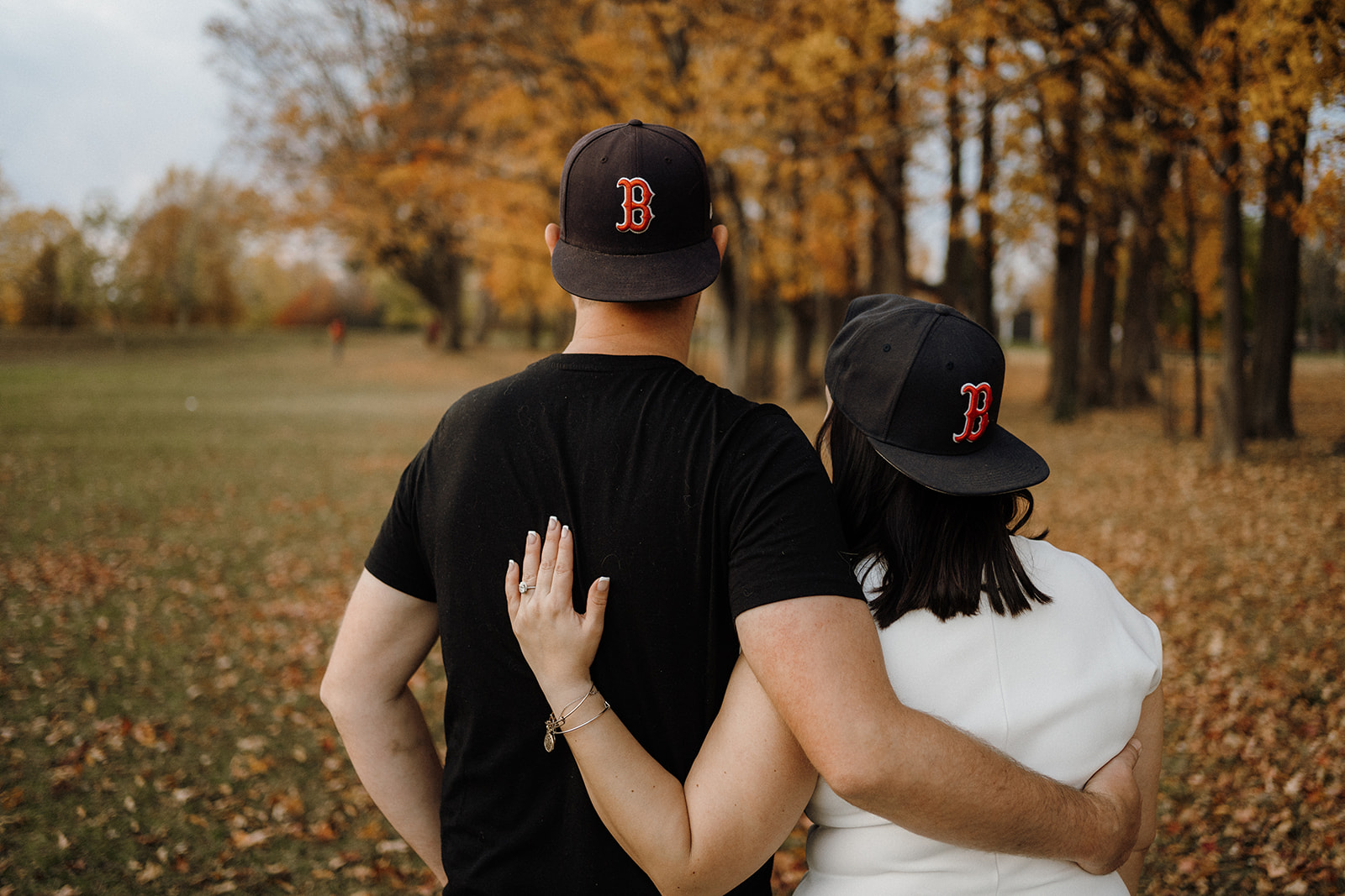 A m an and woman wearing Boston hats outside.