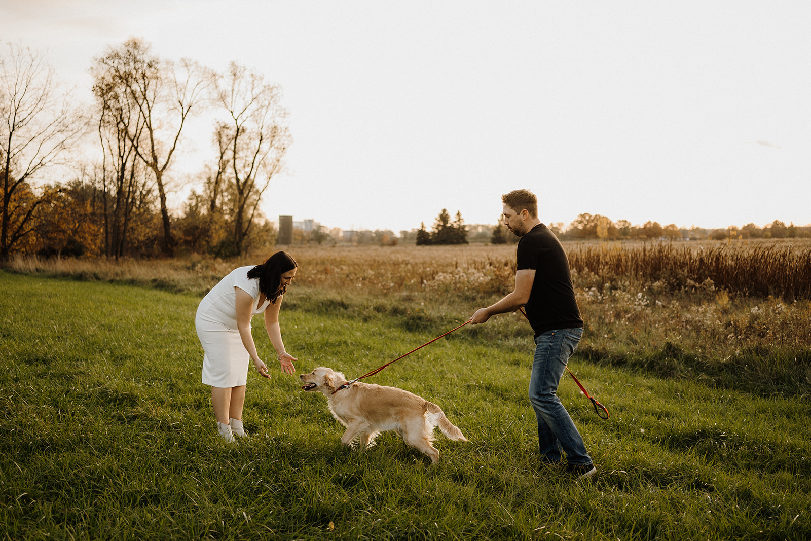 A man and a woman on a field with their dog.