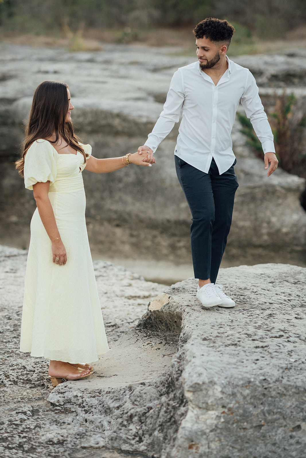 Couple embracing on a boulder during a engagement photography session at McKinney Falls