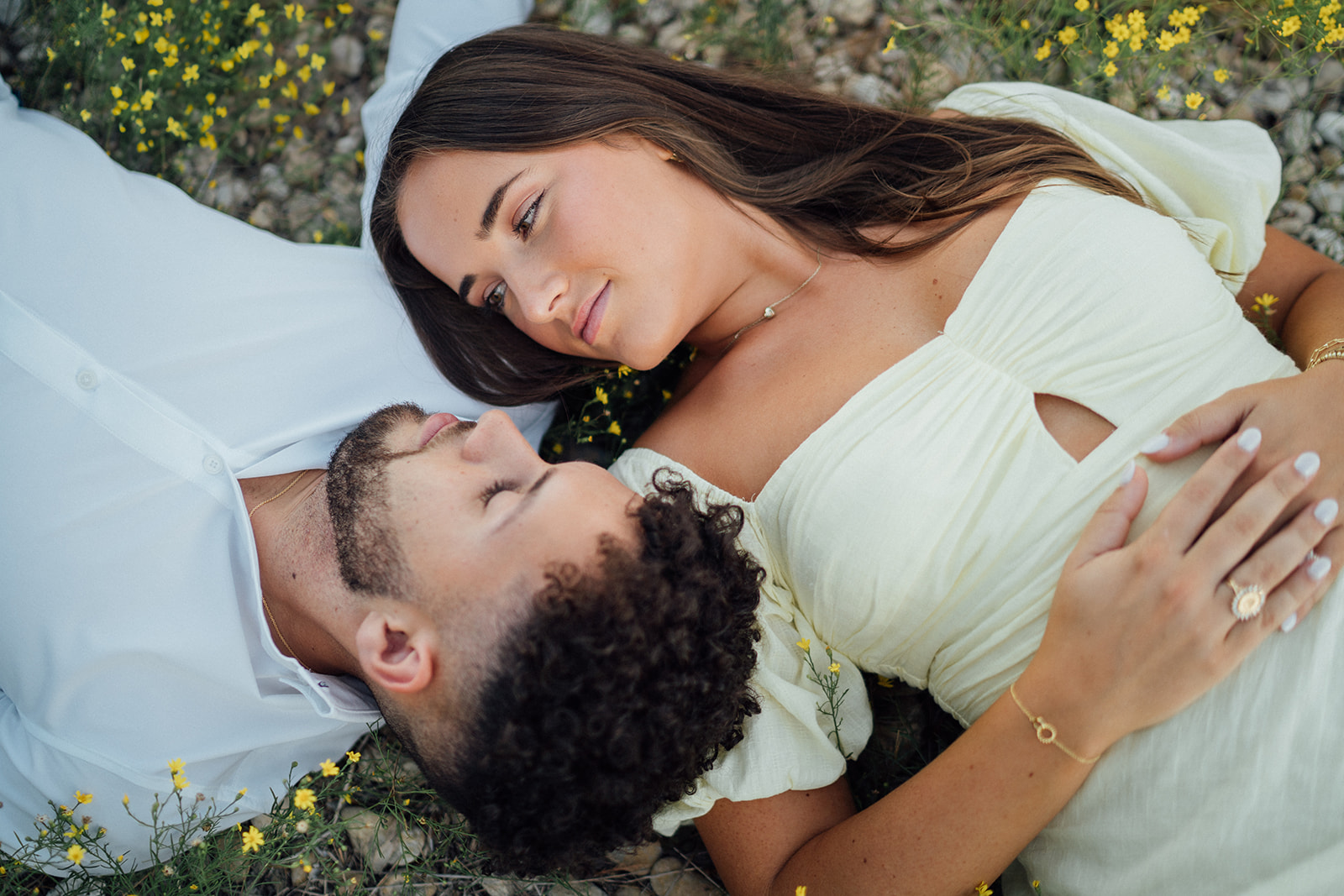 A couple lying on the ground with wildflowers during engagement photography session at McKinney Falls