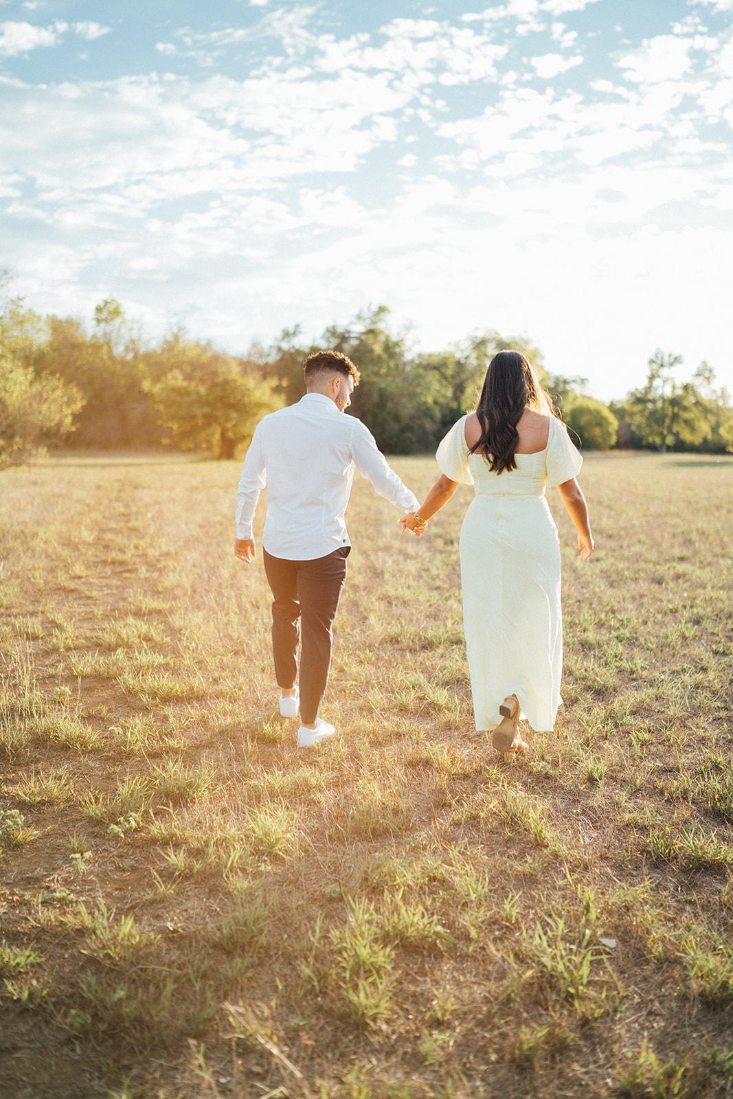 A couple walking away holding hands in a field at McKinney Falls
