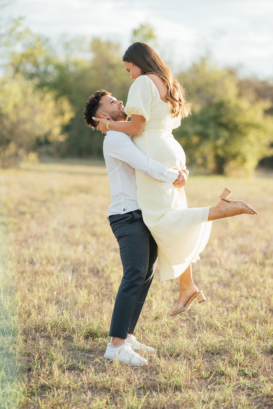 A man lifting his bride to be into the air during a engagement photography session at McKinney Falls