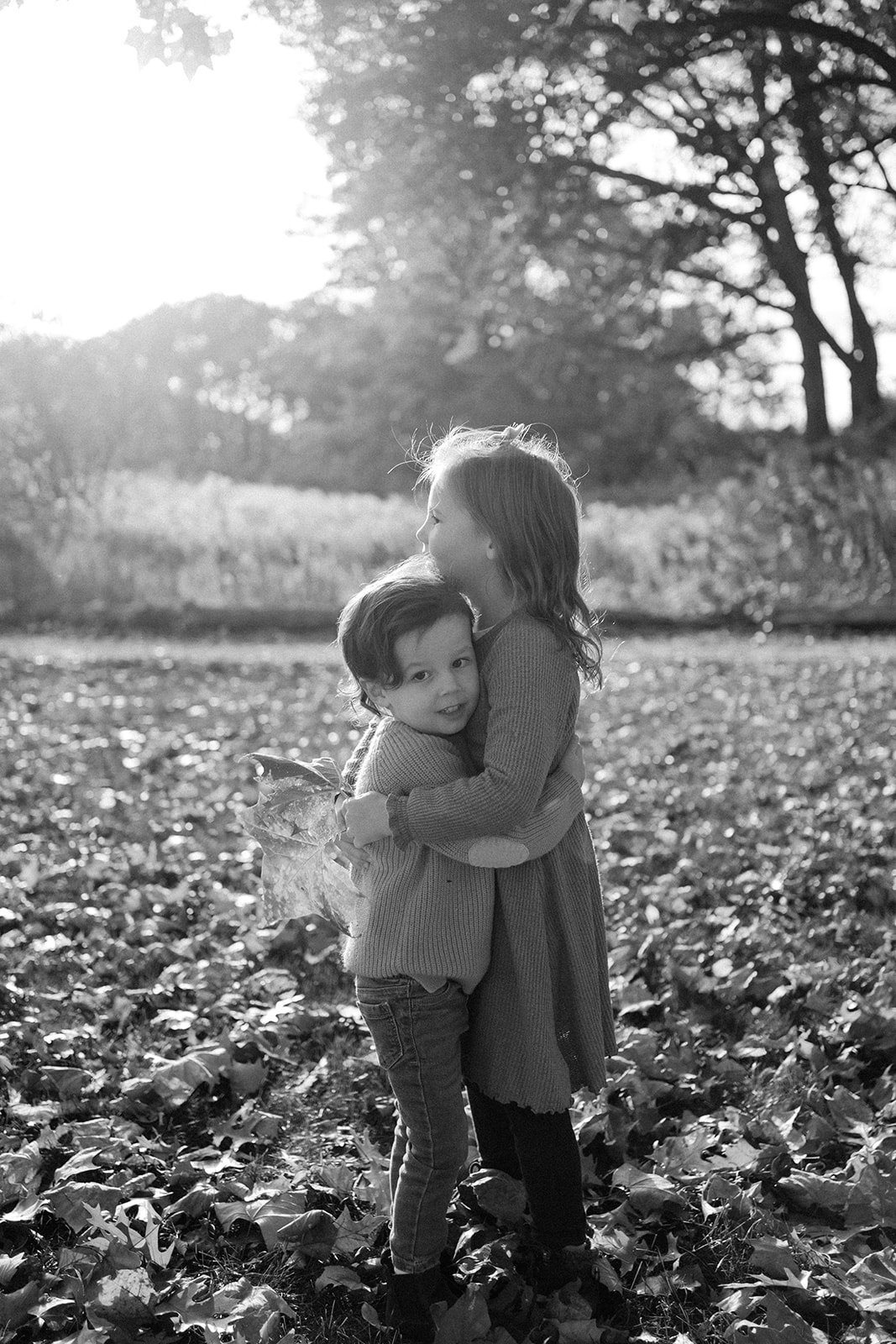 Brother and sister hugging outside.