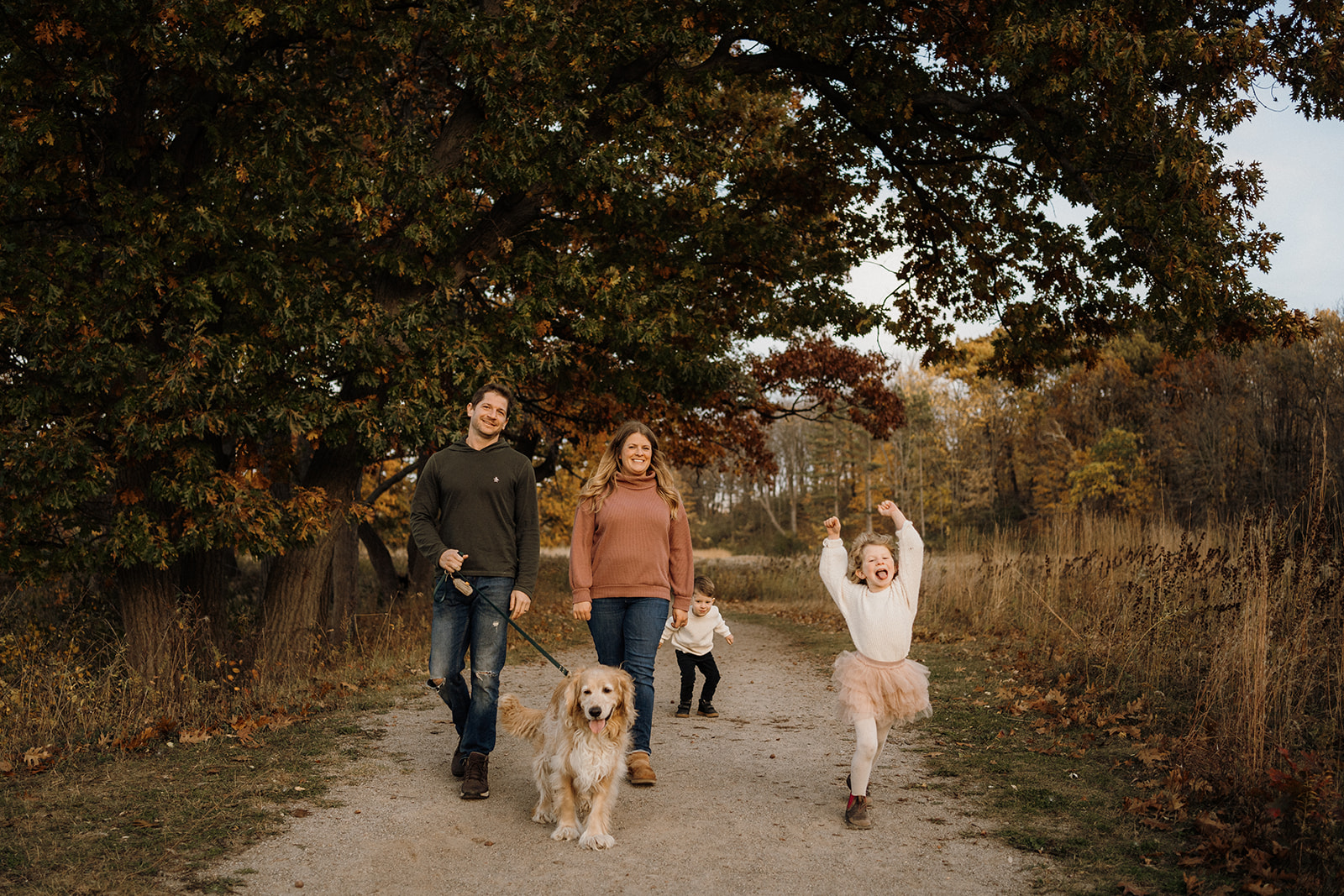 A family of four walking down the path with their golden retriever.  