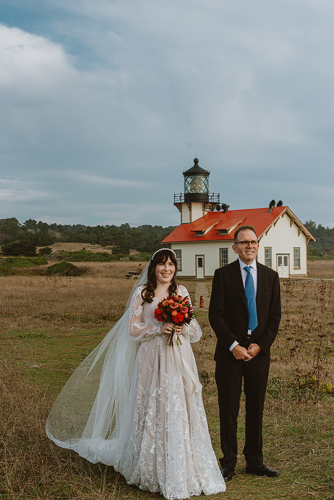 a bride and her father pictured walking down the aisle with the point cabrillo lighthouse as their backdrop