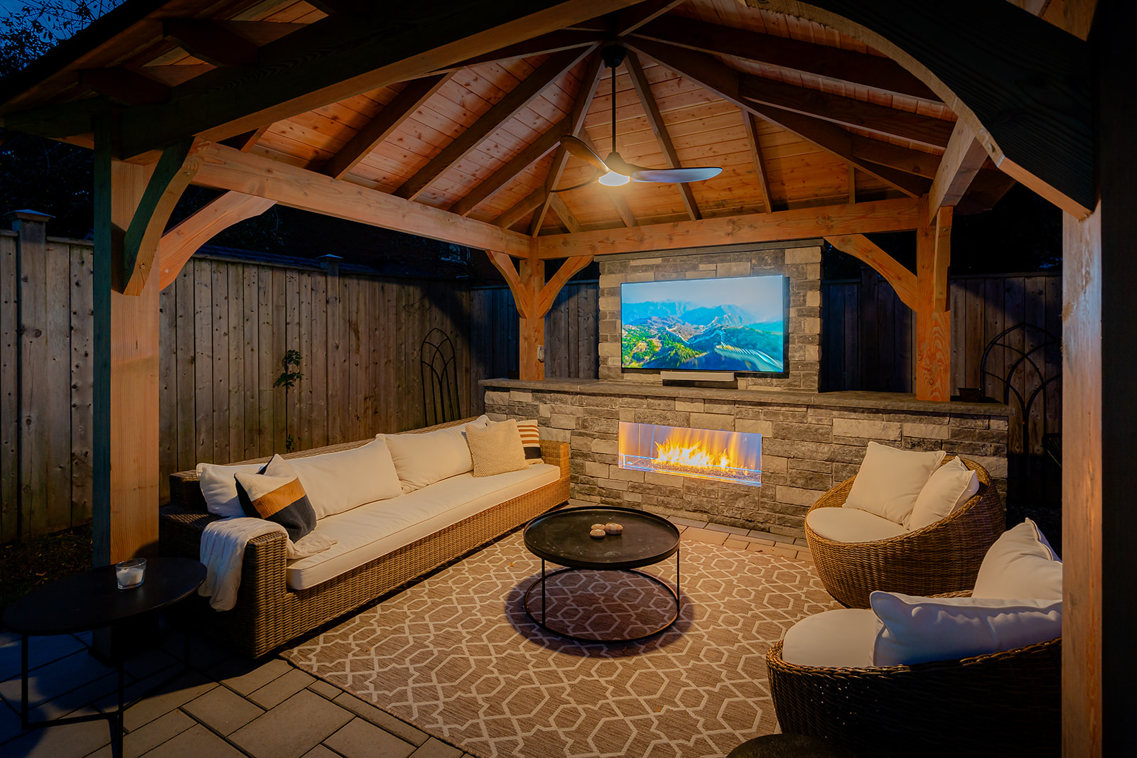 An outdoor patio set with the tv on underneath the gazebo.